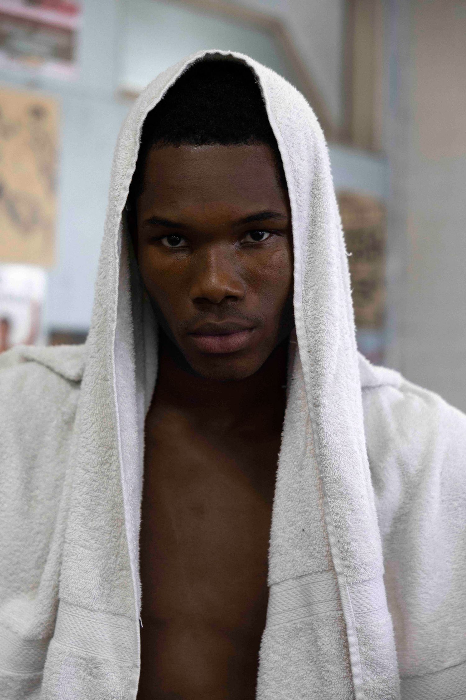 Athletic figure wearing white hooded towel after boxing workout.