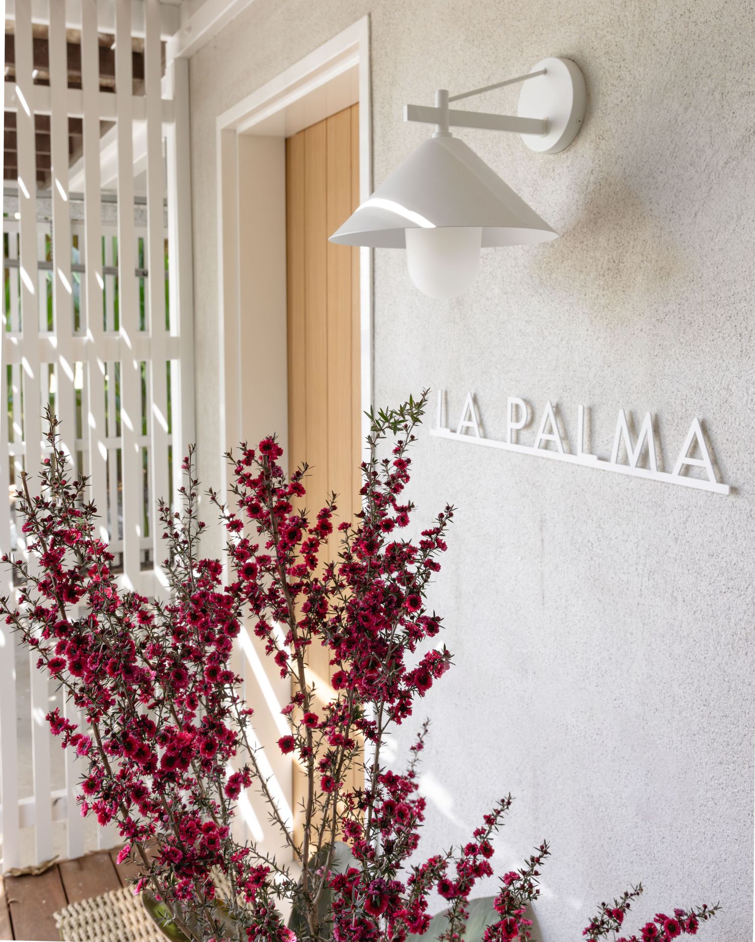 Modern white interior space with burgundy floral arrangements and minimalist wall signage.