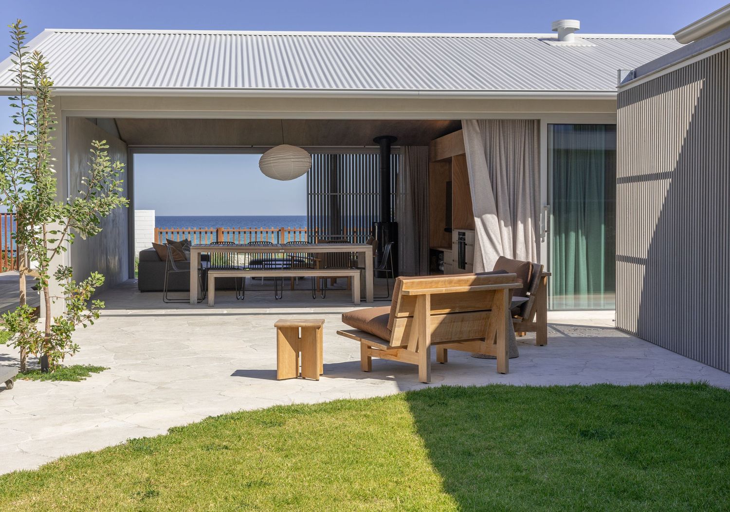 Modern house patio with wooden deck, white walls, grass lawn and elegant landscaping features.