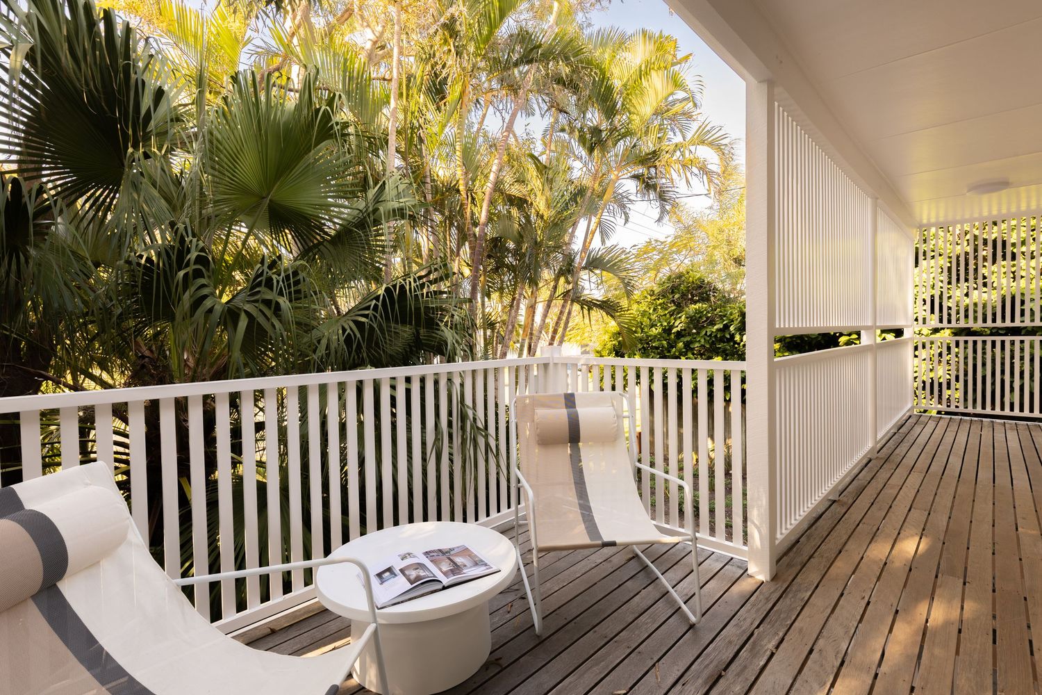 A panoramic view of a white-railed balcony deck surrounded by tropical palm trees and lush foliage.