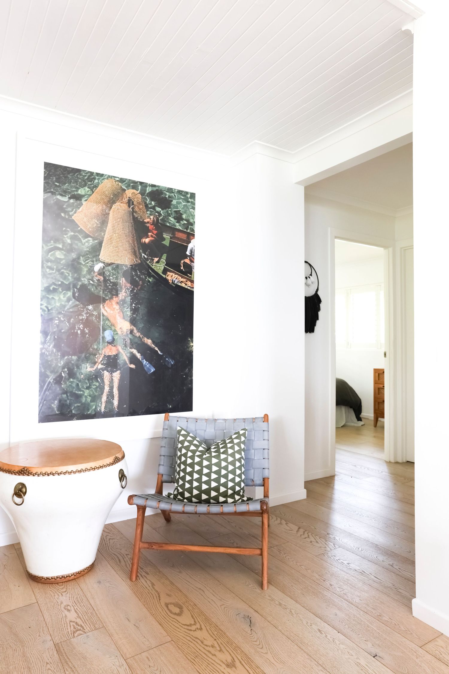 Modern interior space featuring white walls, wood flooring, and contemporary chair with artistic photographs displayed.