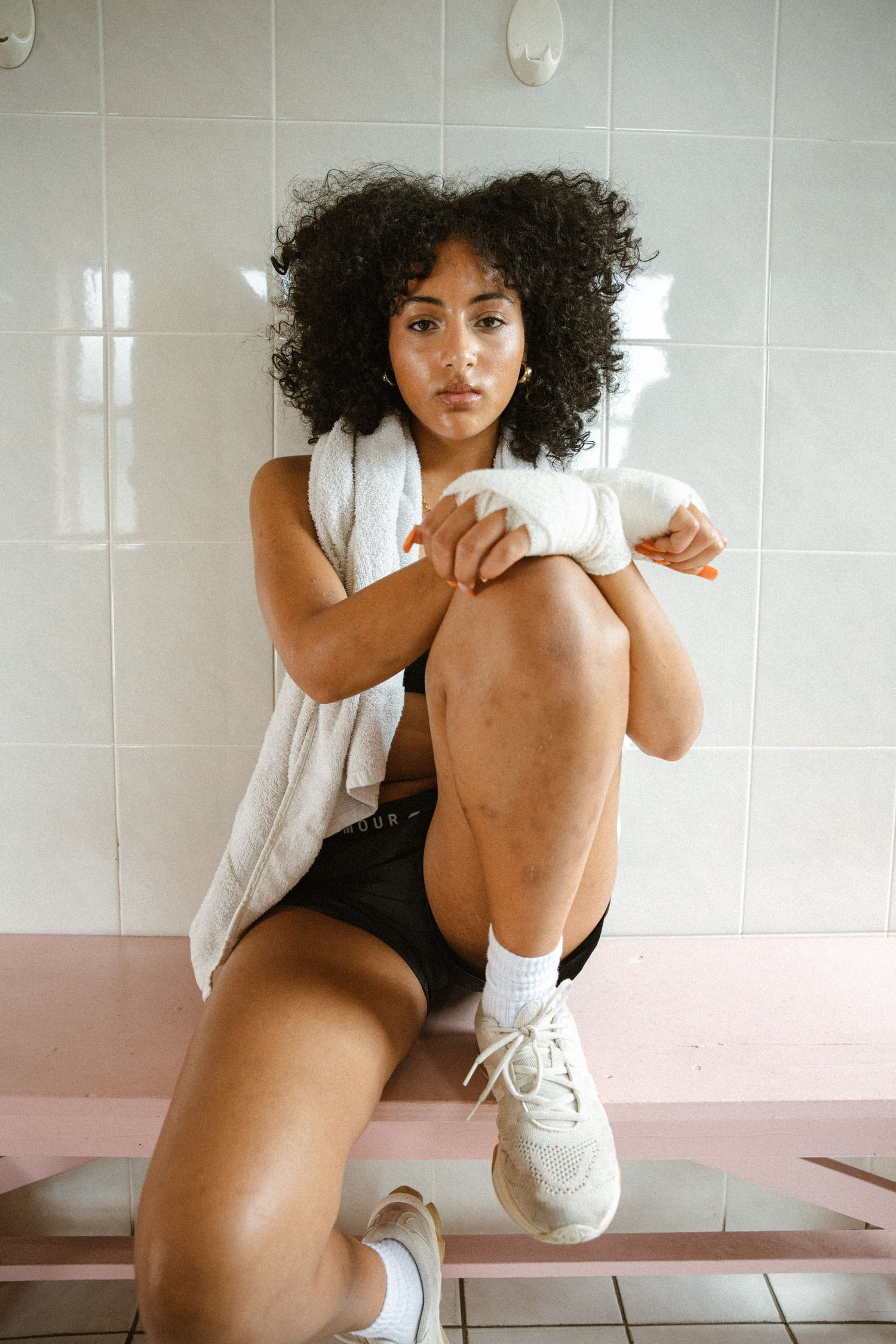 Fitness photo featuring white sneakers and athletic wear in tiled bathroom setting.