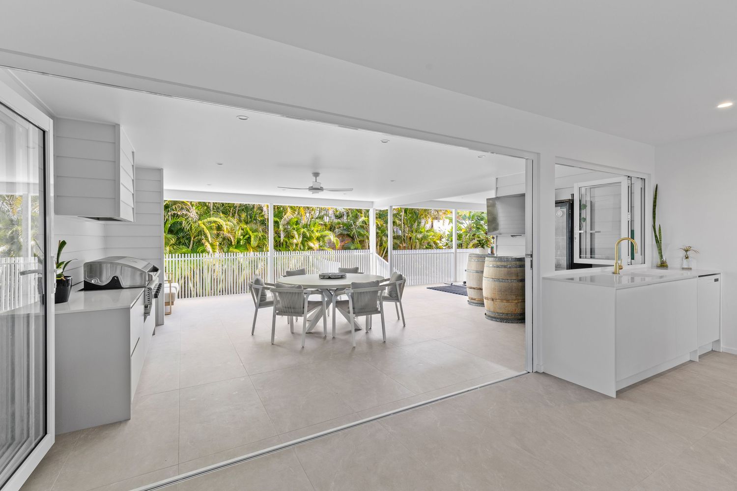 Modern white kitchen opens to spacious dining area with floor-to-ceiling windows and natural light.