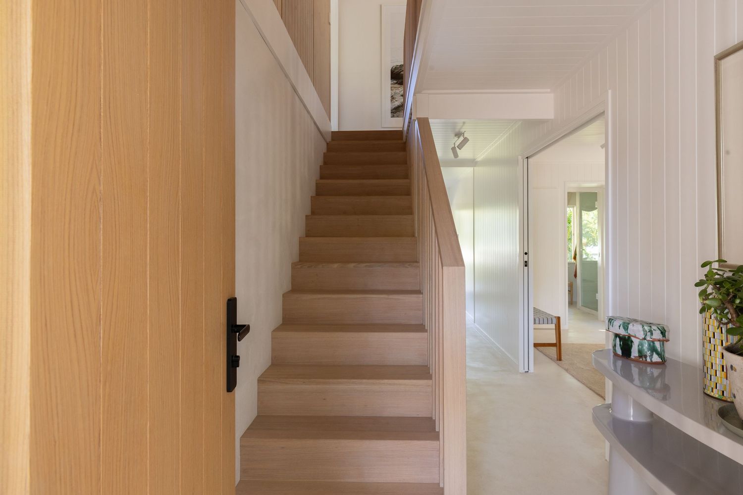 Modern staircase with white walls and wooden steps leading upstairs in a residential home interior.
