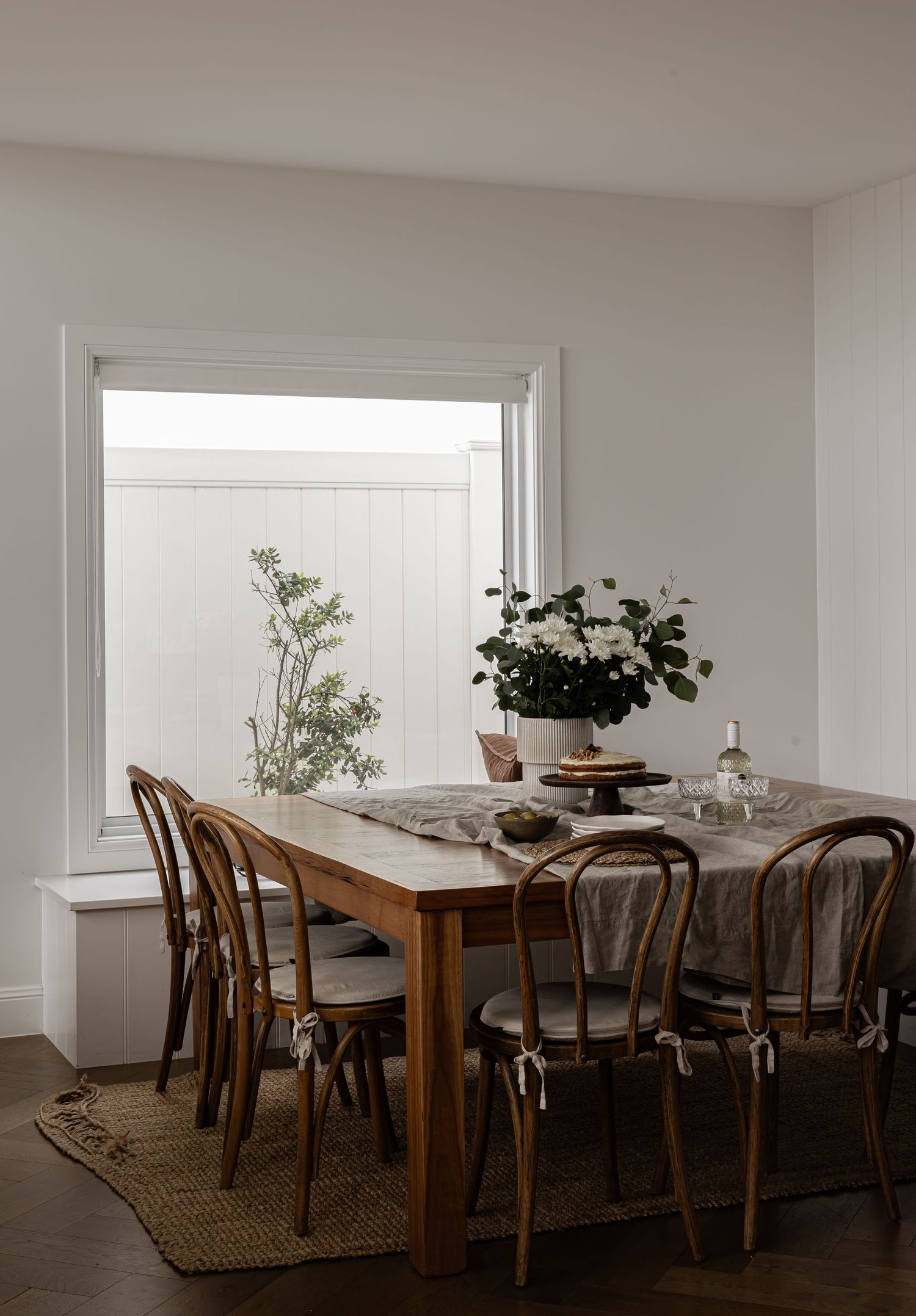 Modern dining room with natural wood table, bentwood chairs and jute rug shown in different views and angles.