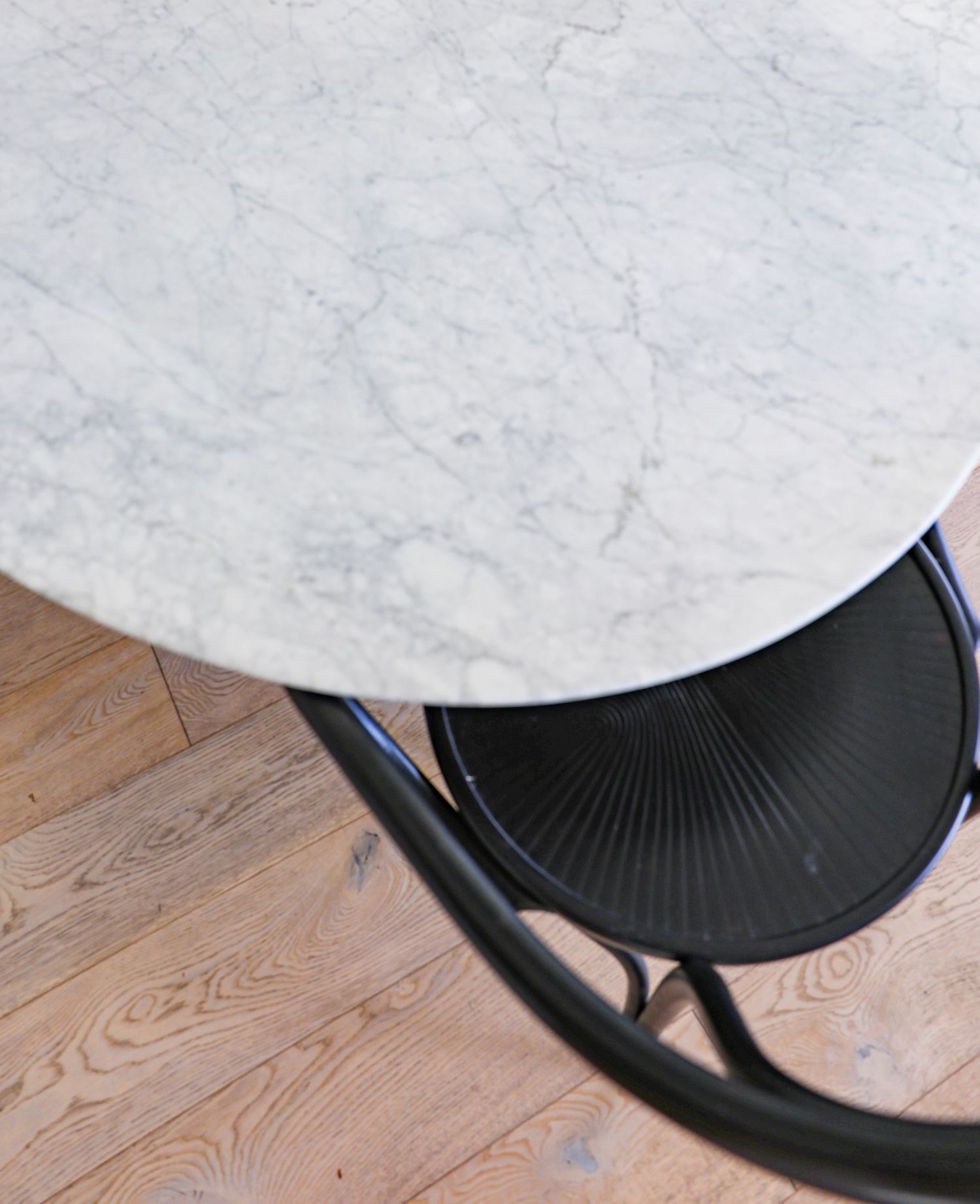 Five side-by-side photos show a black hand fan being opened progressively on a white table against a wooden floor.