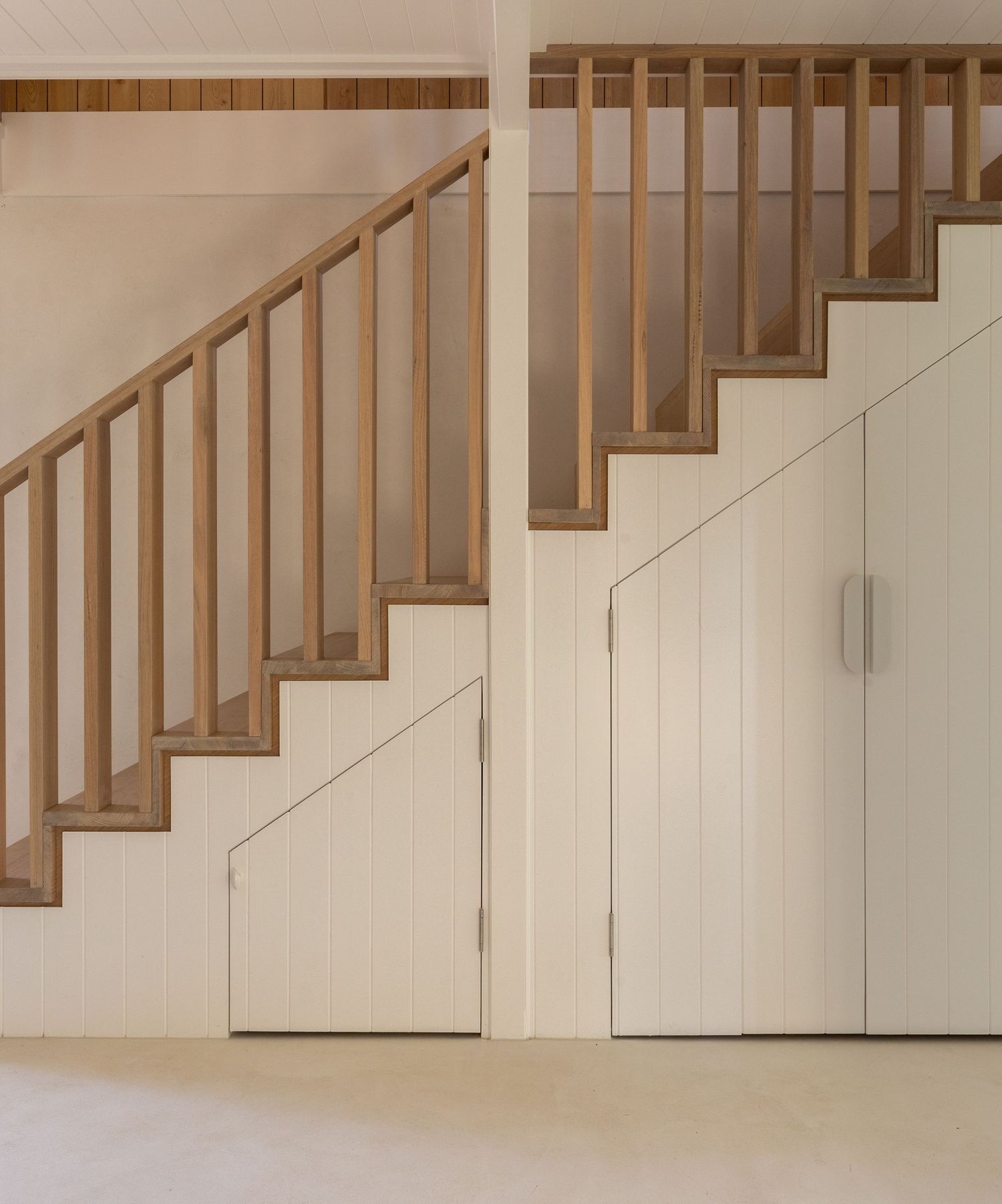 Modern wooden staircase with white walls and under-stair storage featuring clean lines and minimalist design.