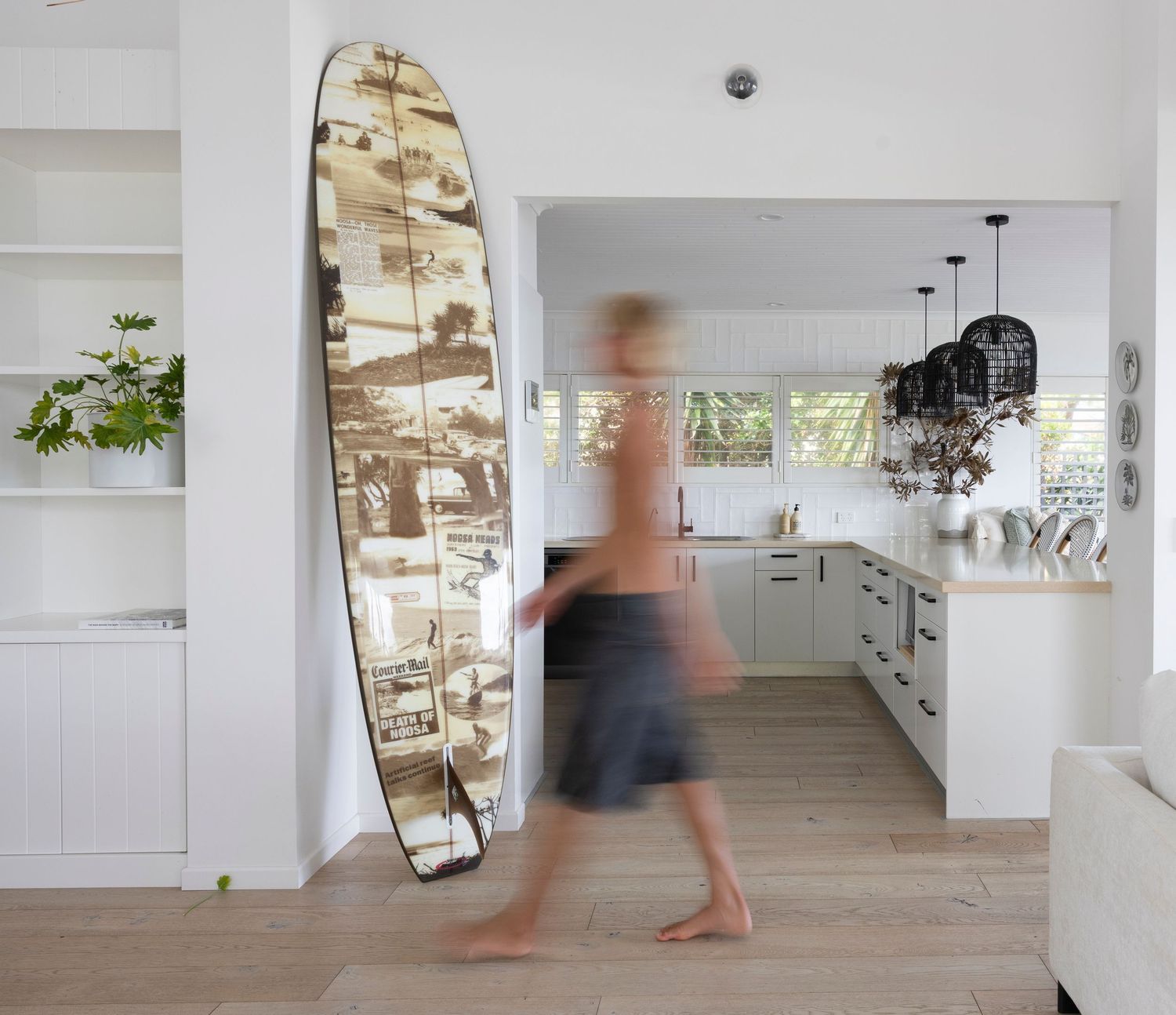 Modern white kitchen interior with large decorative mirror and hardwood floors in contemporary home design.