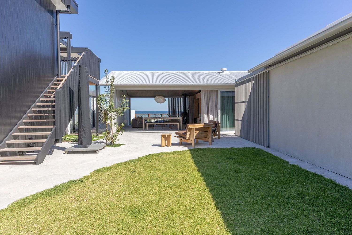 Contemporary house exterior with grassy yard, outdoor seating area, and exterior staircase.