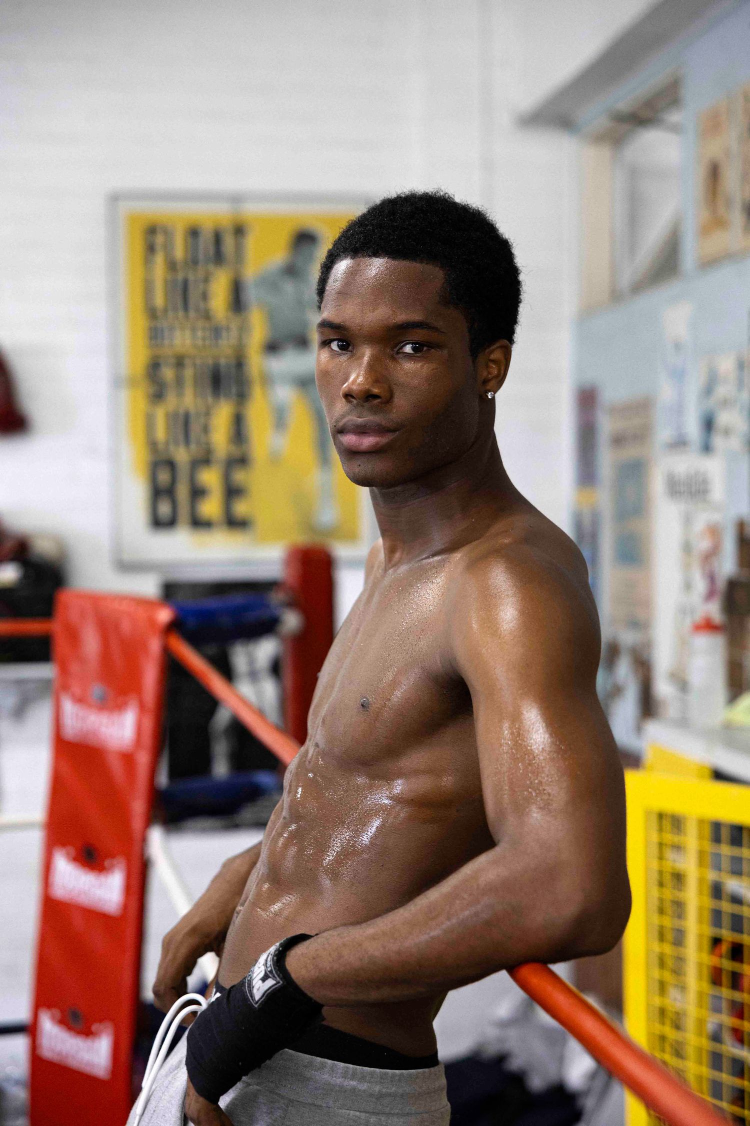 Athletic boxer takes break during training session in boxing gym with motivational posters.