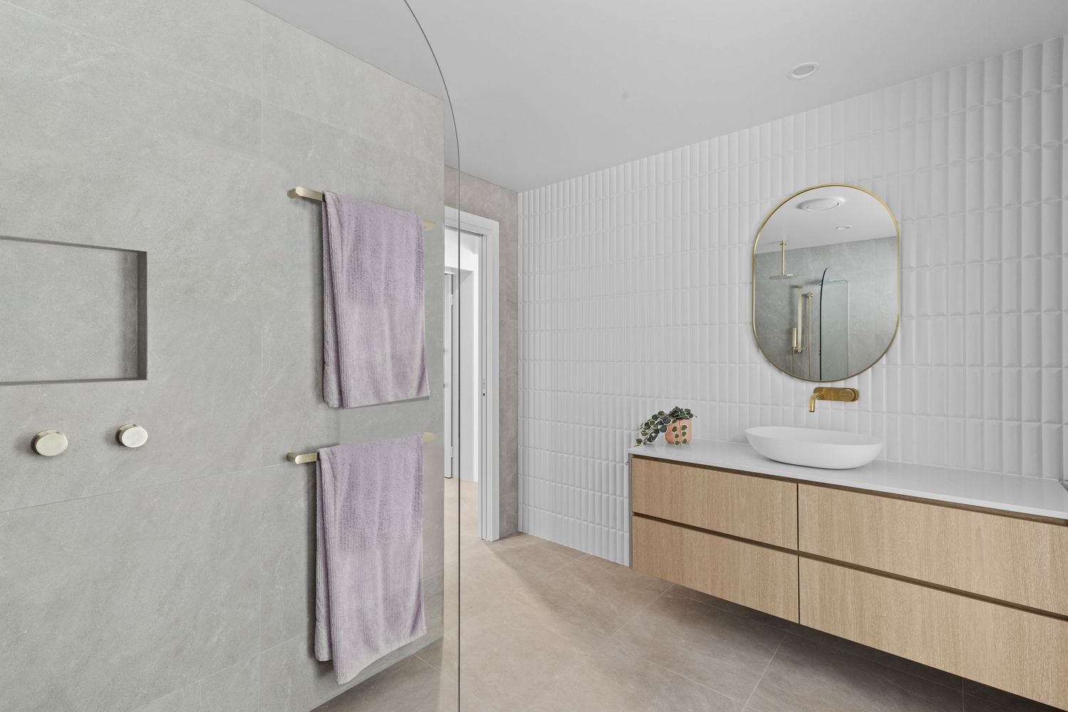 Modern white bathroom interior features vertical wall paneling and light wood vanity with round mirror.