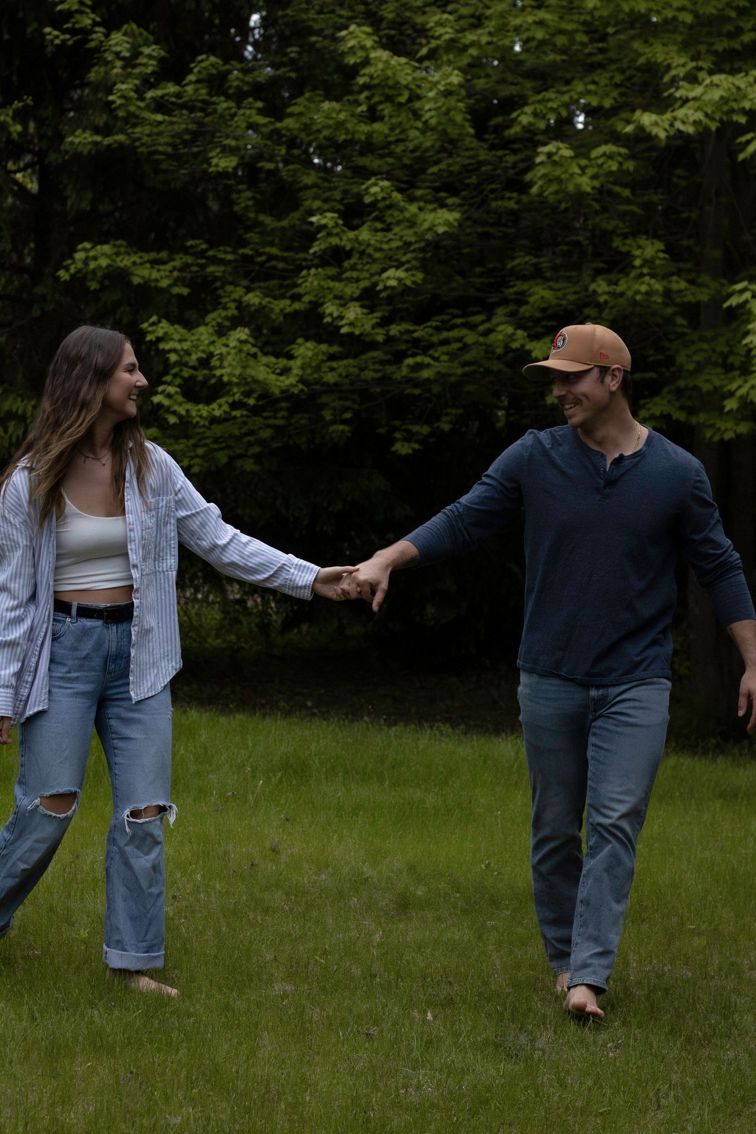 Couple falling down in slow motion sequence on grassy meadow in casual denim outfits.