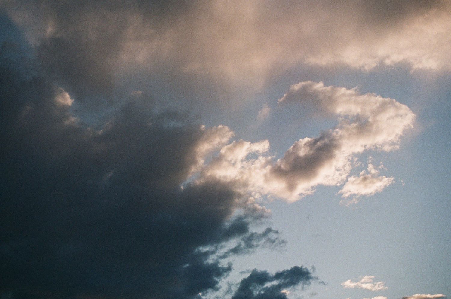 Dramatic cloudy sky with sunlight breaking through dark storm clouds at sunset.