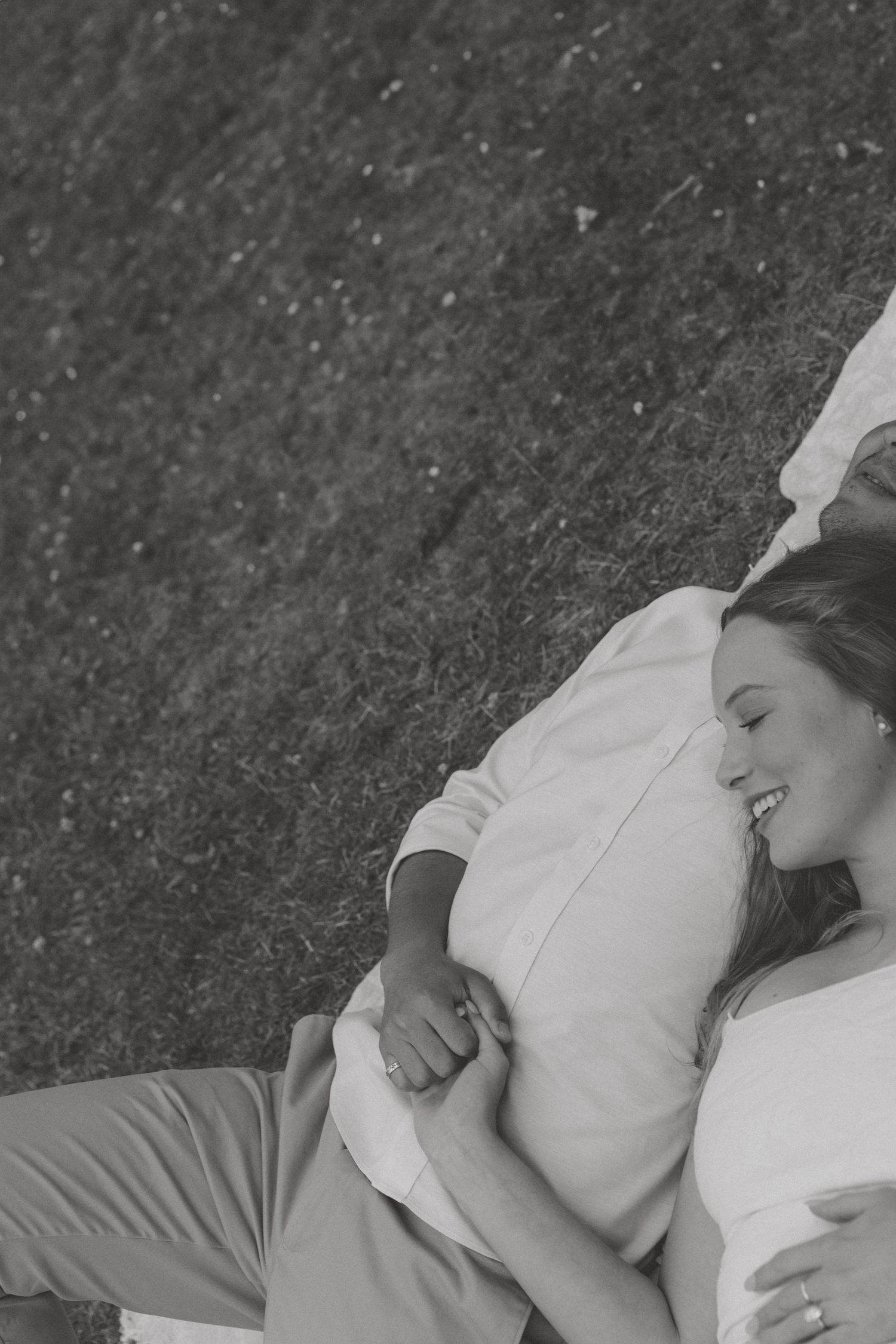 A romantic black and white series of figures laying on a textured surface, captured from above.