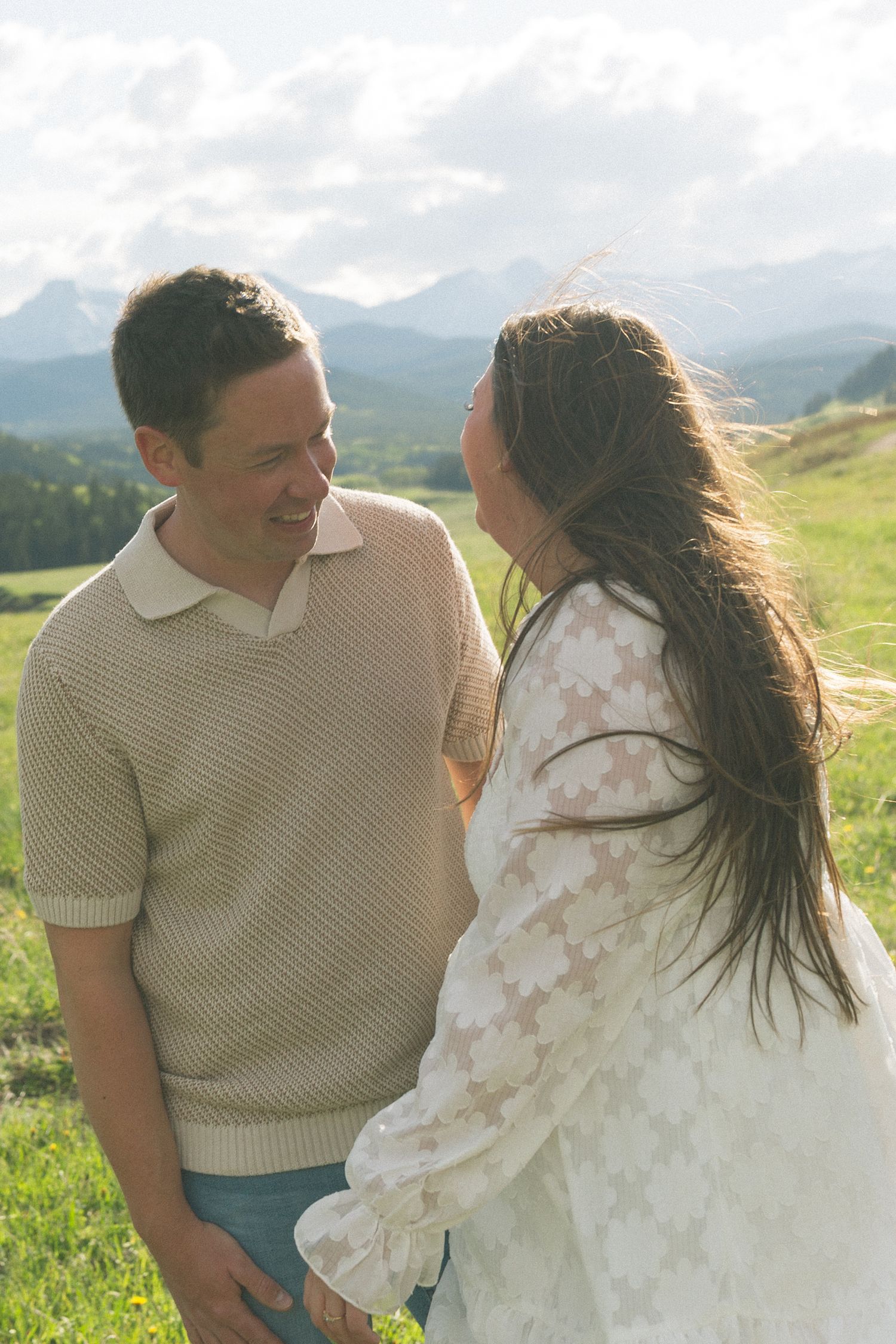 Two people sharing an intimate moment on a scenic mountain meadow.