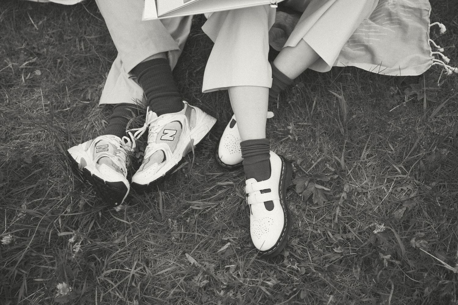 Close-up view of white sneakers and feet on grass.