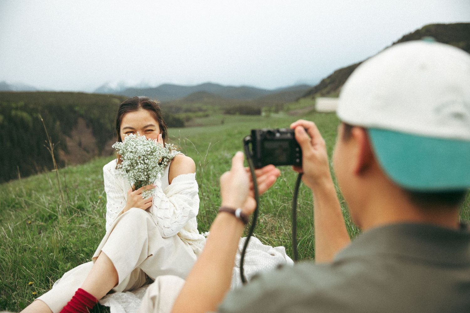 A photoshoot moment on a scenic hillside with mountains in the background.