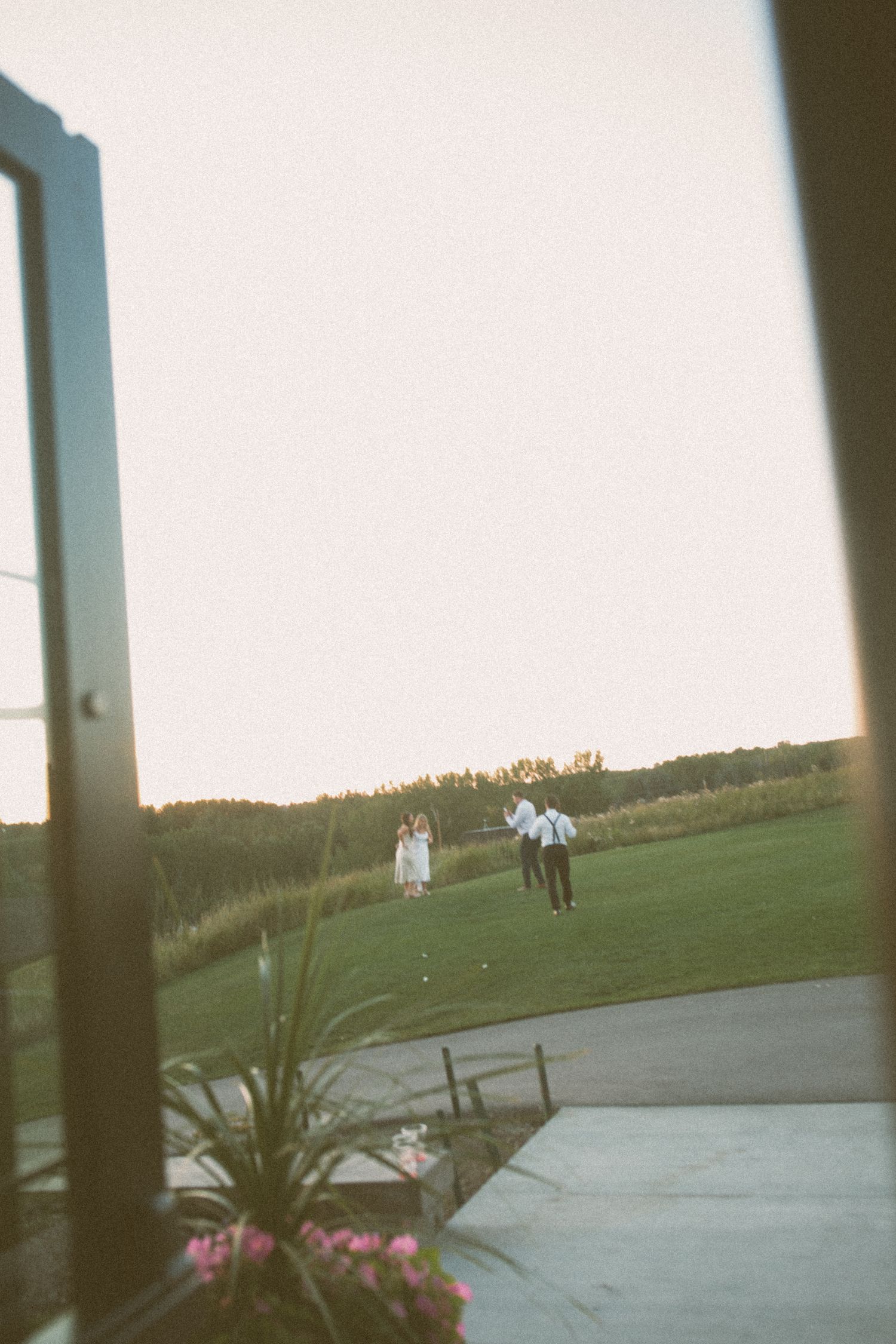A distant view of people walking on a golf course with flowers in the foreground.