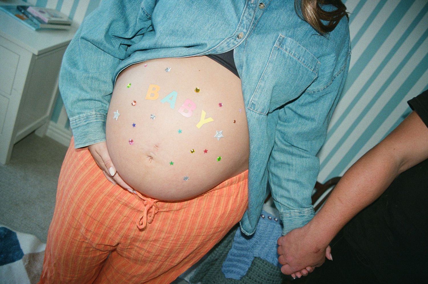 A series of five photos showing a growing baby bump in orange and teal maternity clothing during pregnancy progression.