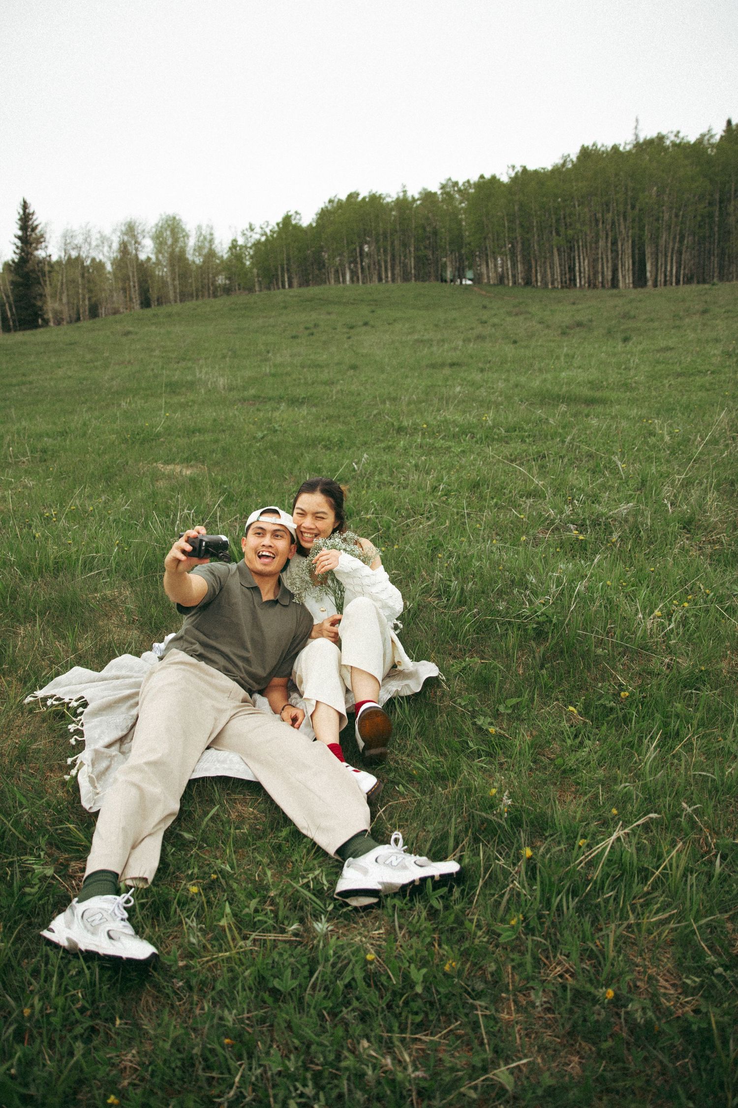 A joyful moment shared on a grassy hillside with trees in the background.