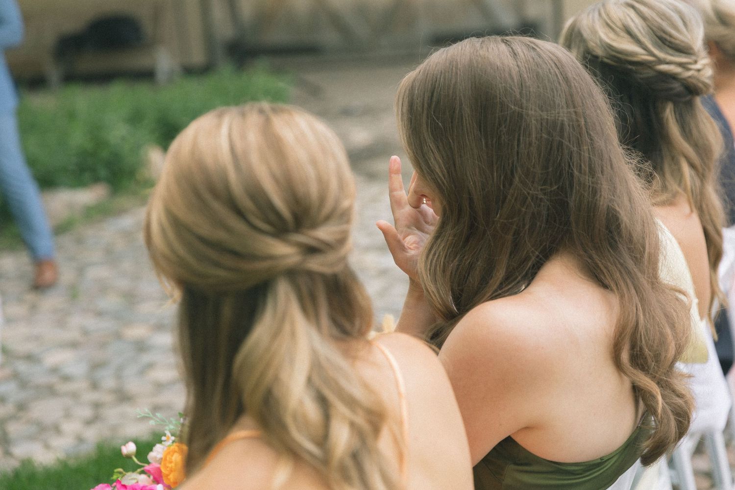Wedding attendees in formal dresses gather outdoors on a summer day.