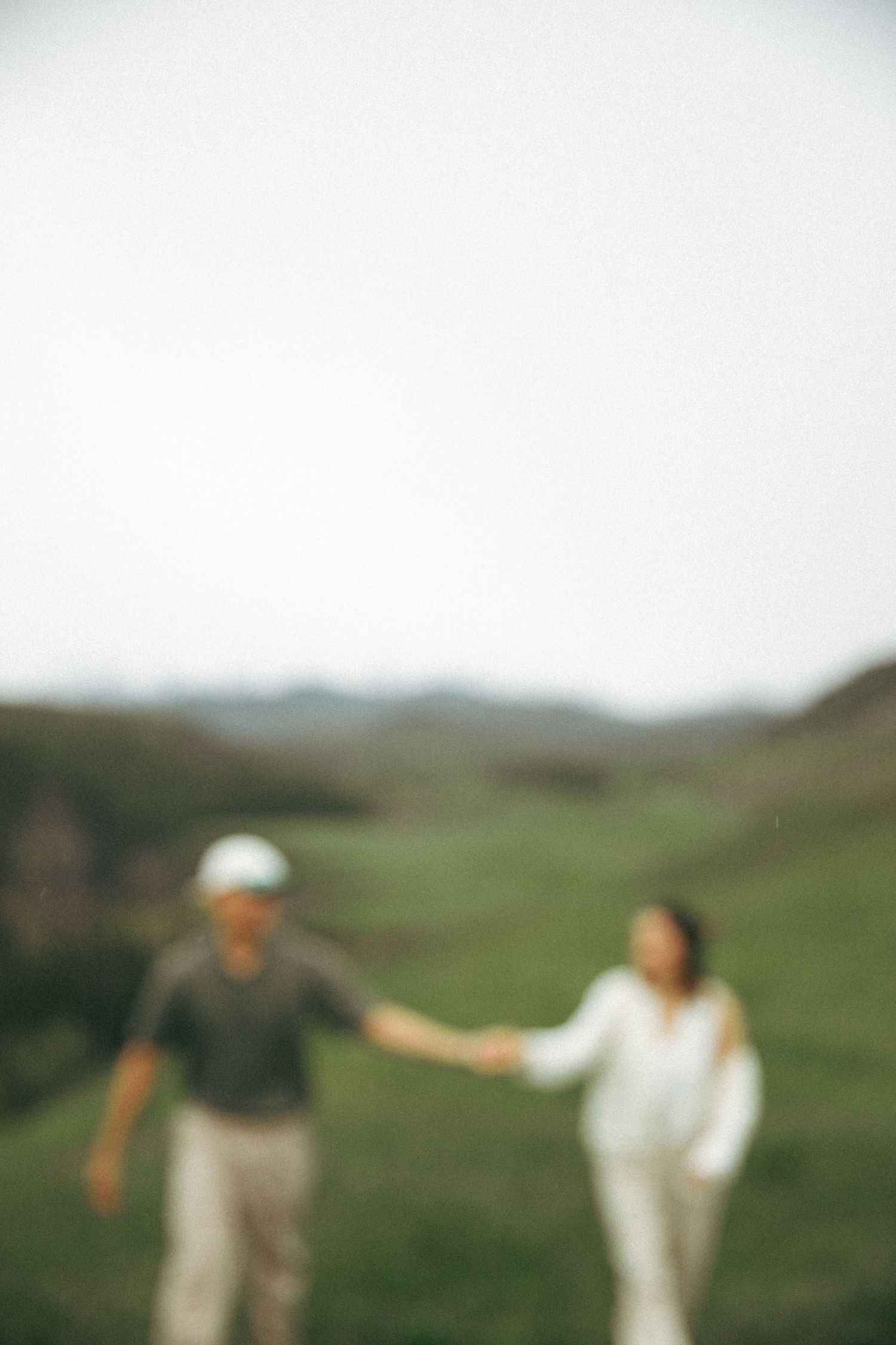 Blurred image of two people walking together on a grassy hillside.