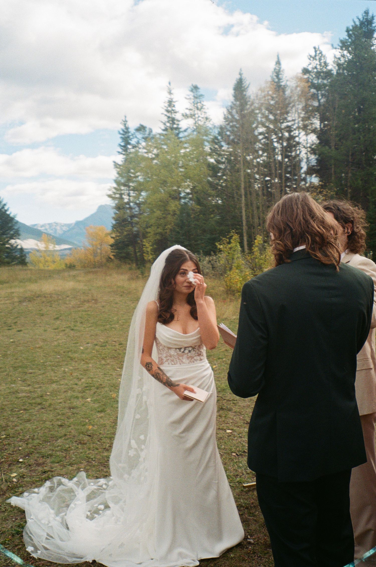 A couple enjoying a beautiful mountain wedding ceremony surrounded by evergreen trees on a scenic hillside.