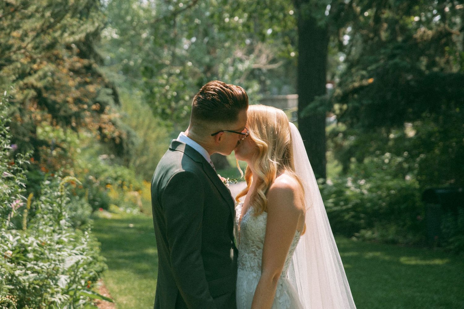 Intimate wedding couple moment captured in a sun-dappled garden setting.