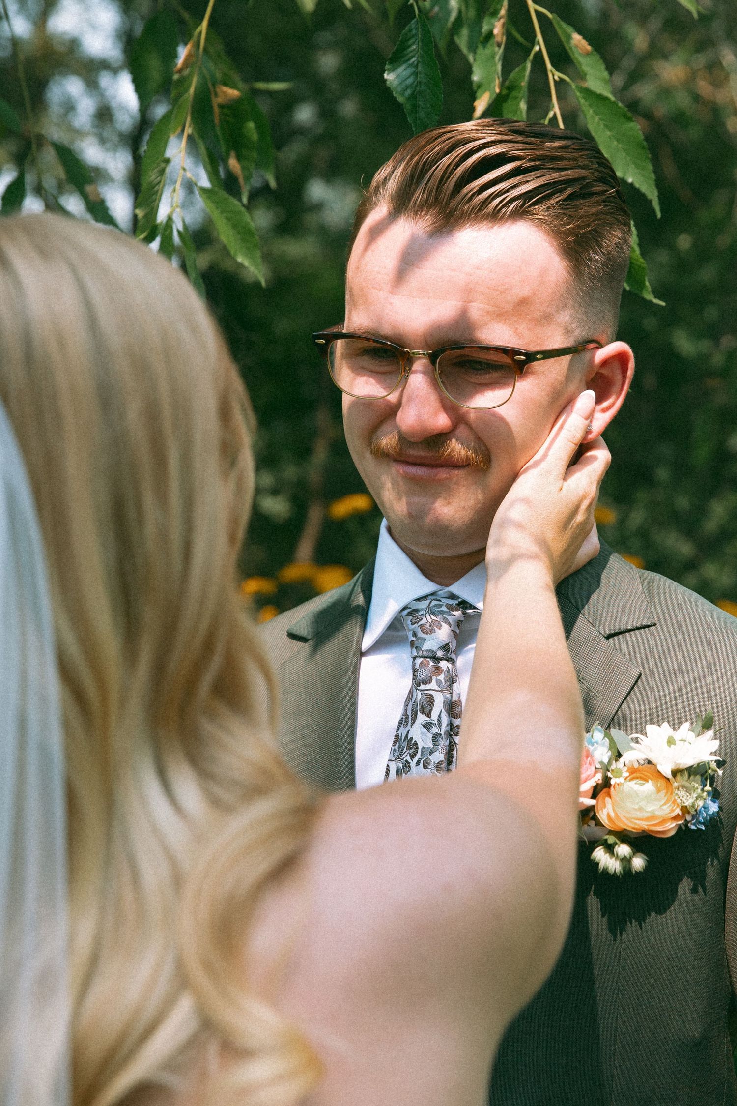 A tender wedding moment captured between newlyweds in a garden setting.