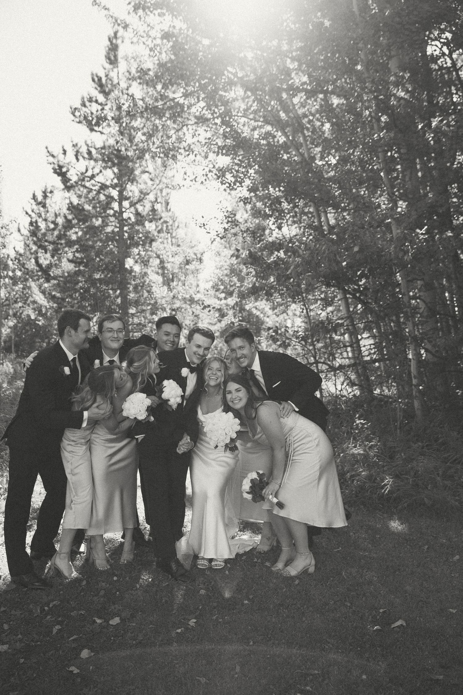 Black and white photo of wedding party gathered closely for group portrait.