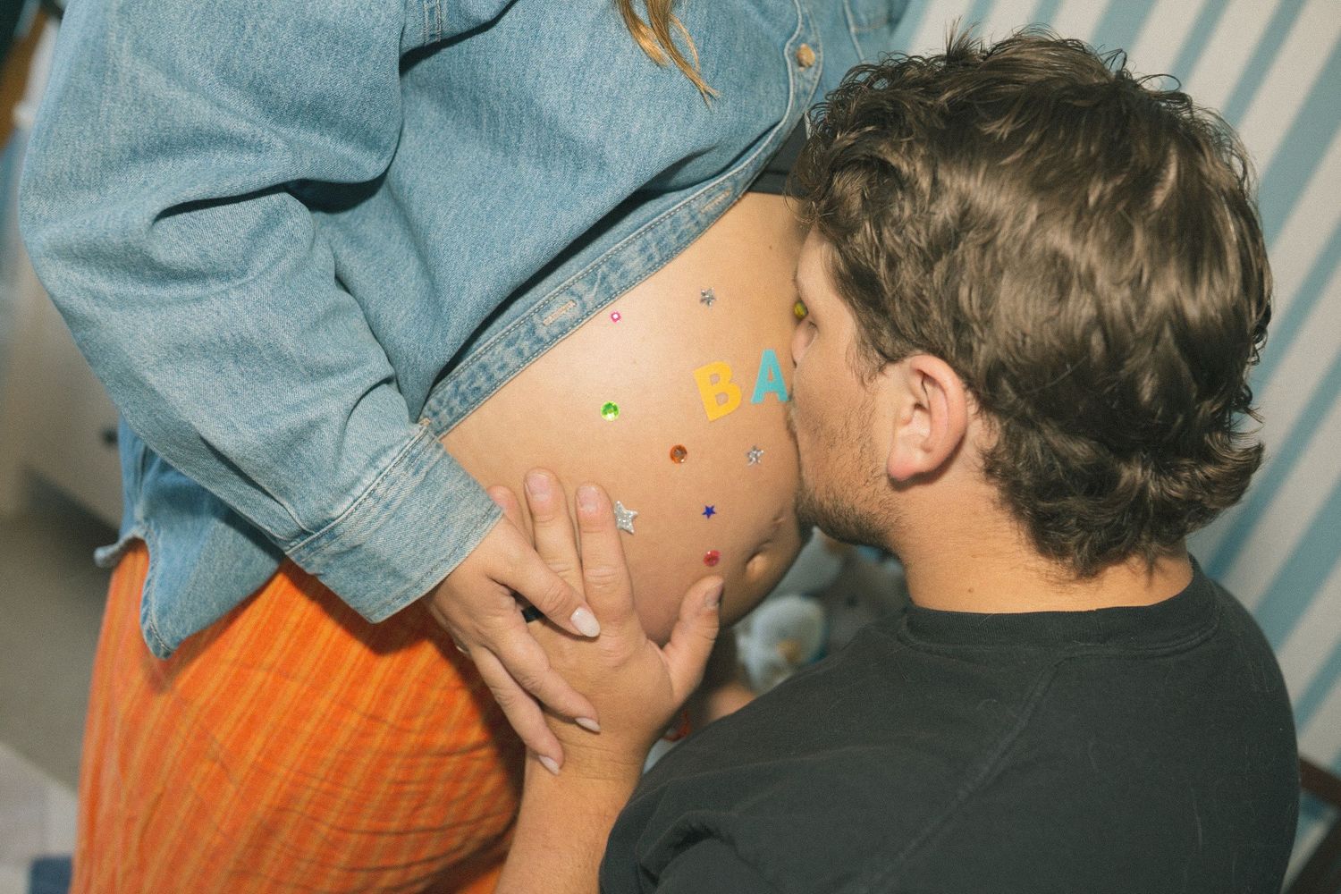 Close-up shots showing people in denim clothing interacting in a striped-wallpapered room.