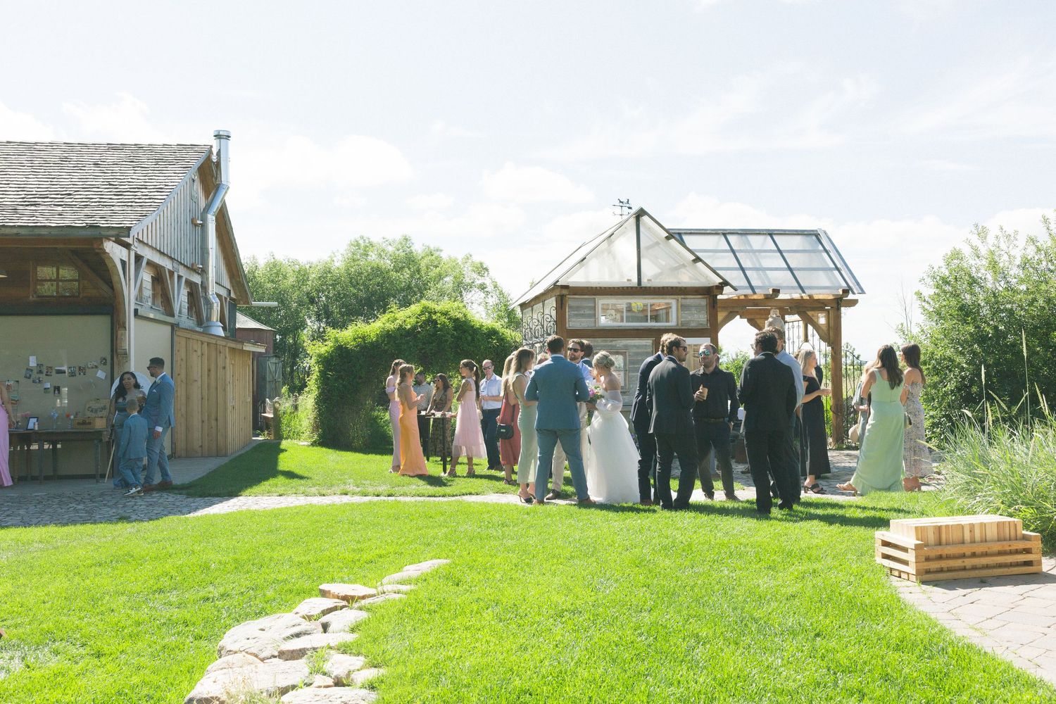 Panoramic view of a rustic outdoor wedding venue with green lawns and wooden structures.