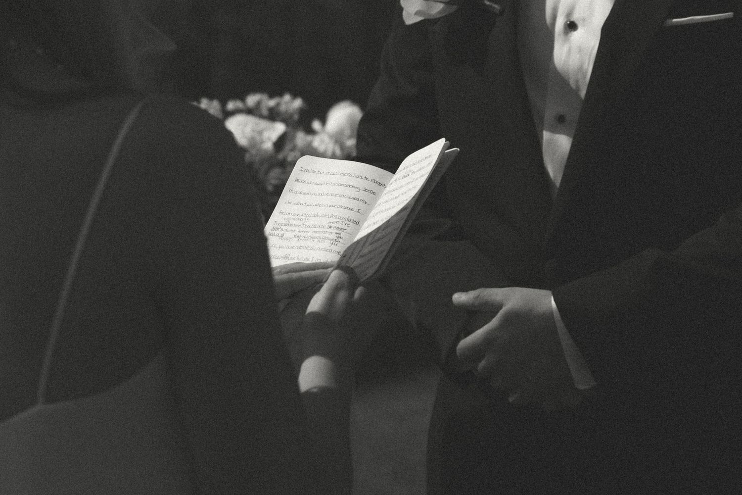 Black and white image of person holding sheet music during formal event performance.