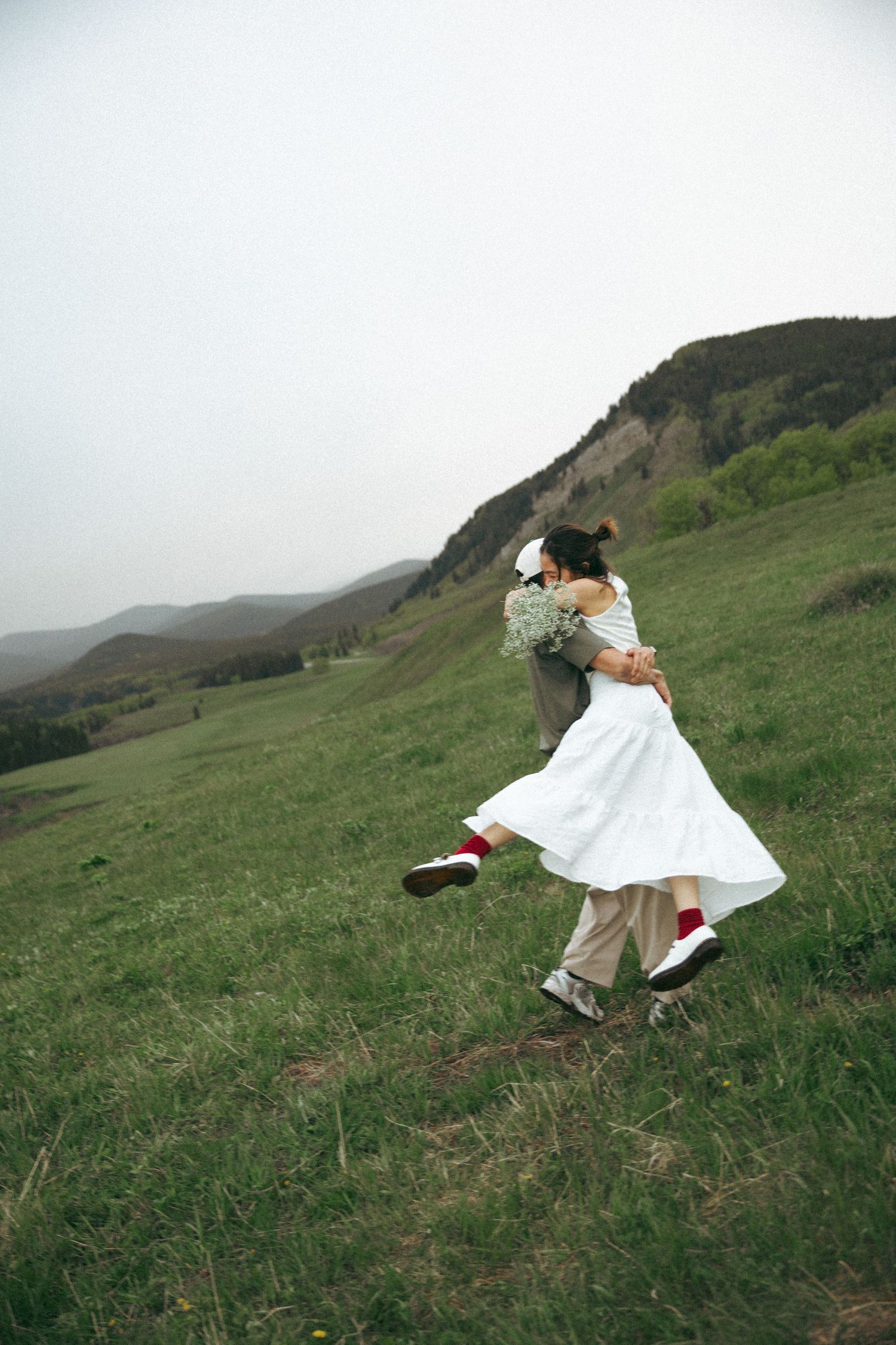 Dancing couple spinning on a hillside with mountains in the background.