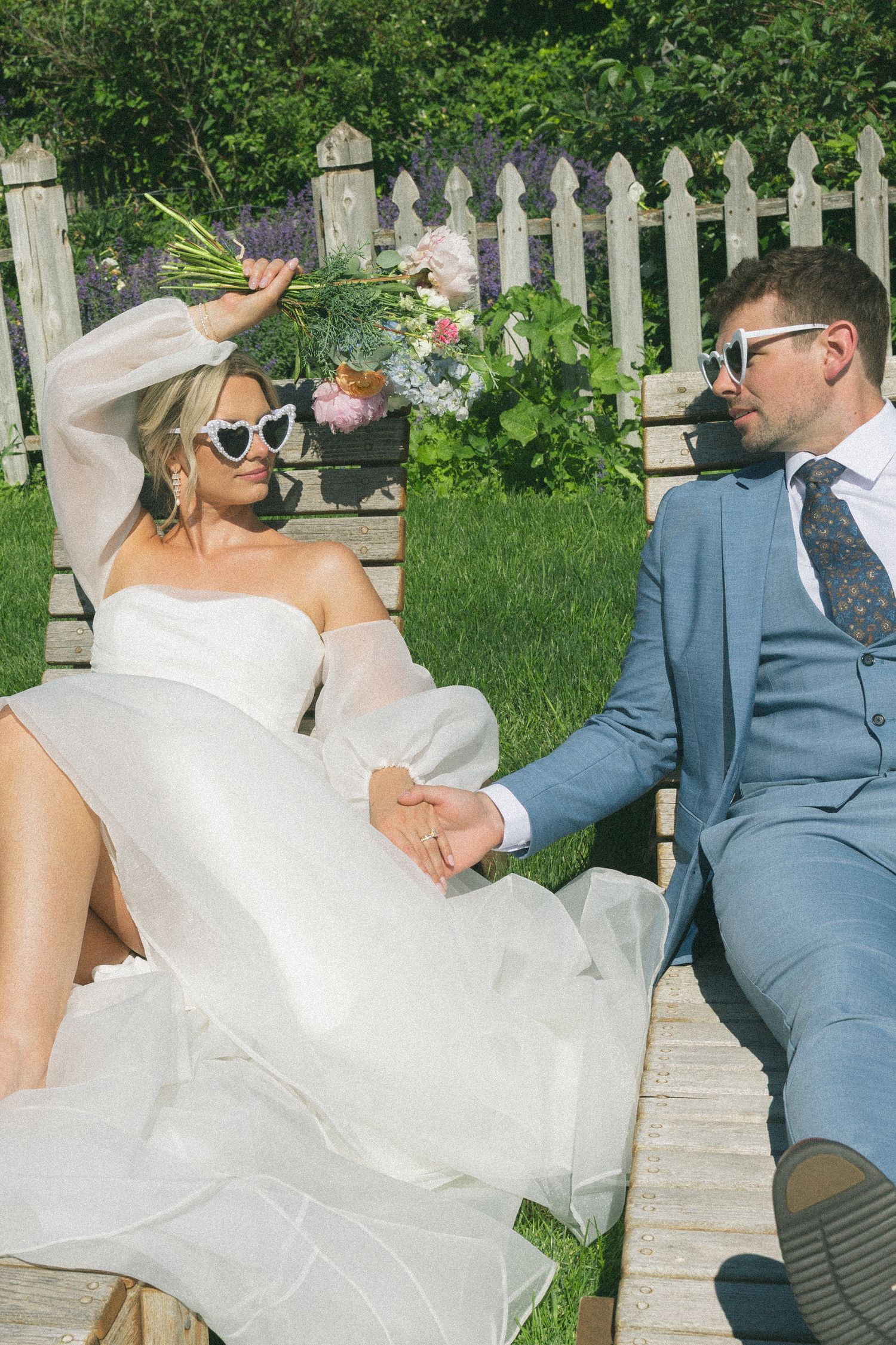 Playful wedding photos on wooden lounge chairs in a sunny garden setting.