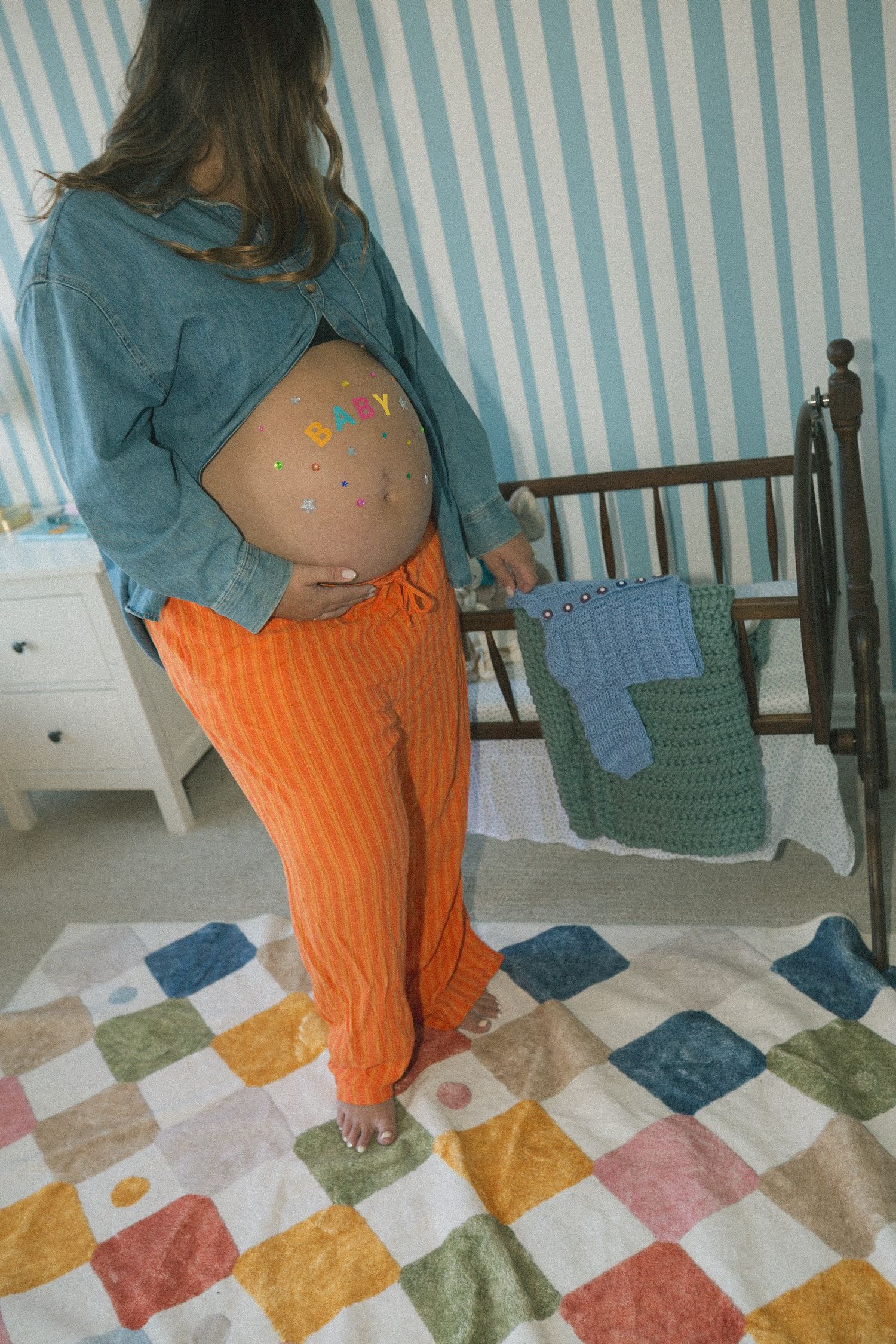 A series of photos showing a pregnant person in orange pants and blue top standing on a colorful patchwork quilt.