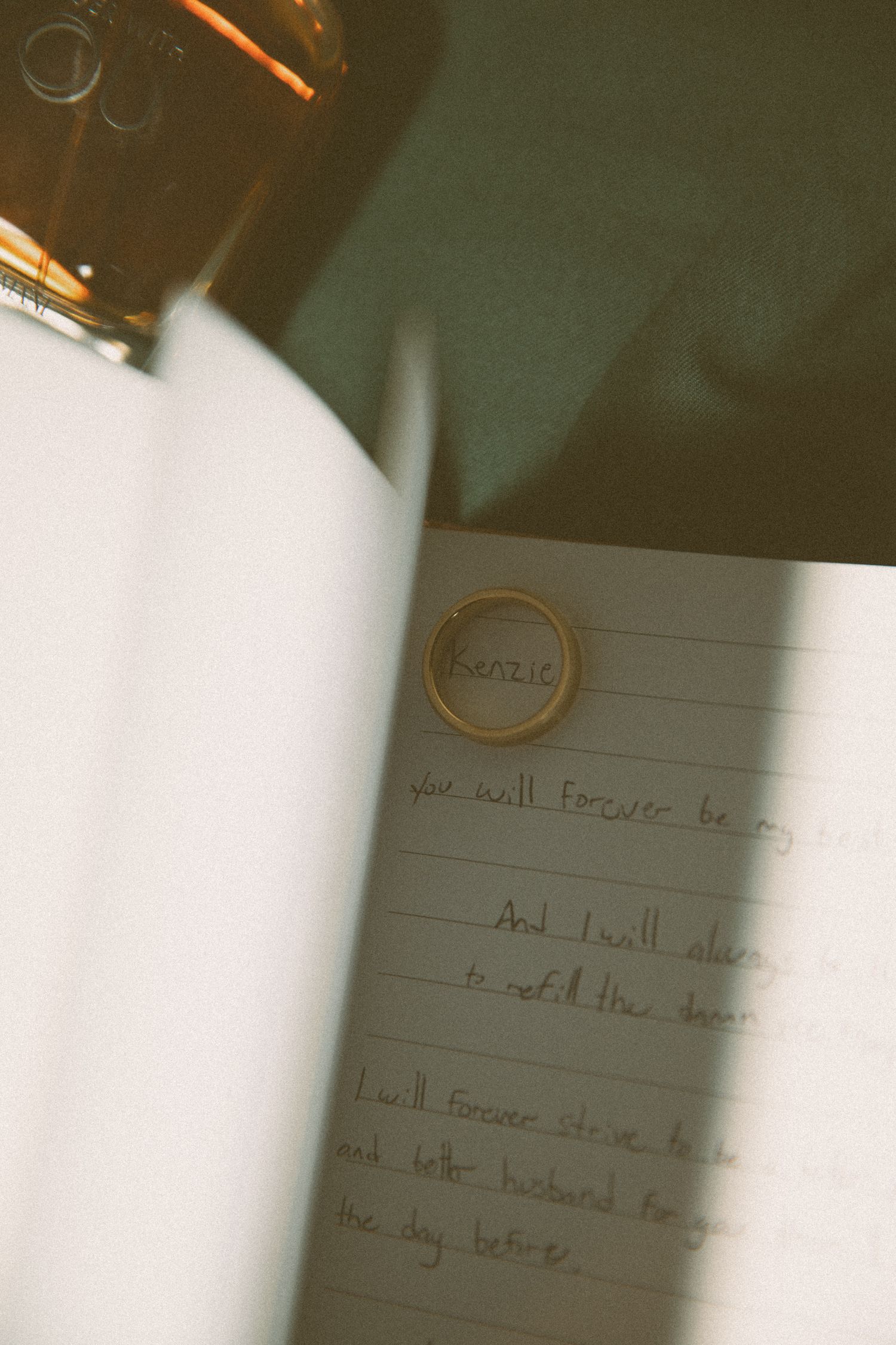 A notebook page with handwritten text and a dark bottle visible at the top of the frame.