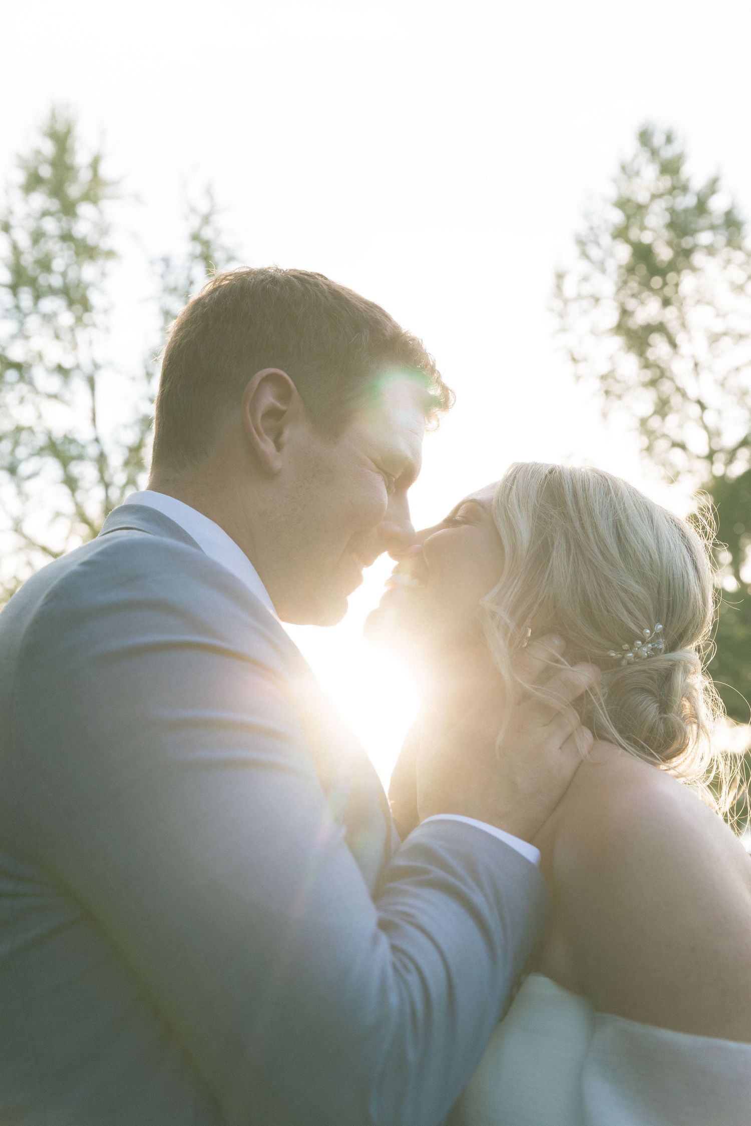 Silhouetted couple sharing an intimate moment at sunset with sunlight creating a romantic backlit glow.