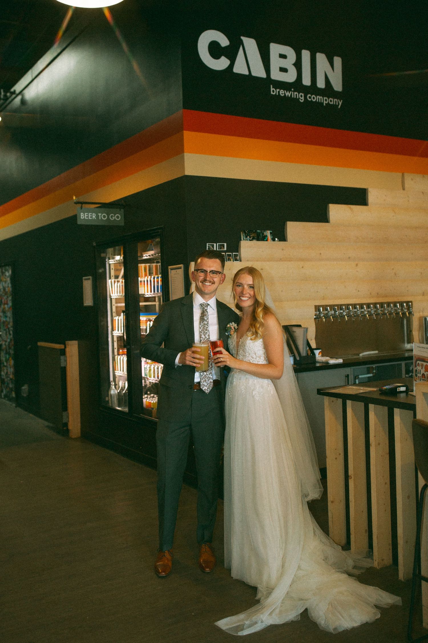 Wedding couple toasting with drinks at Cabin Brewing Company bar.