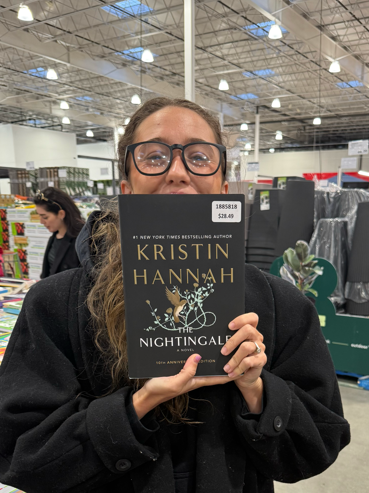 Shopper holding up Kristin Hannah's 'The Nightingale' book in a retail store.