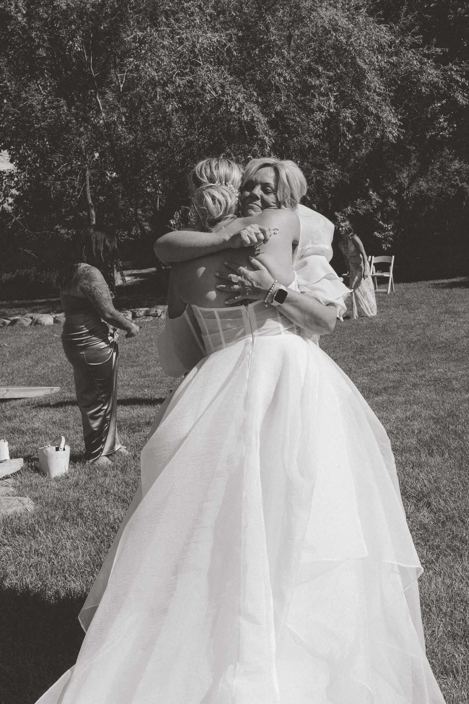 Wedding couple embracing outdoors on a sunny day with bride wearing a full white ballgown dress.