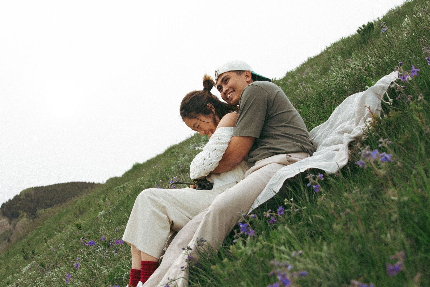 Couple sharing an intimate moment on a hillside covered in wildflowers.