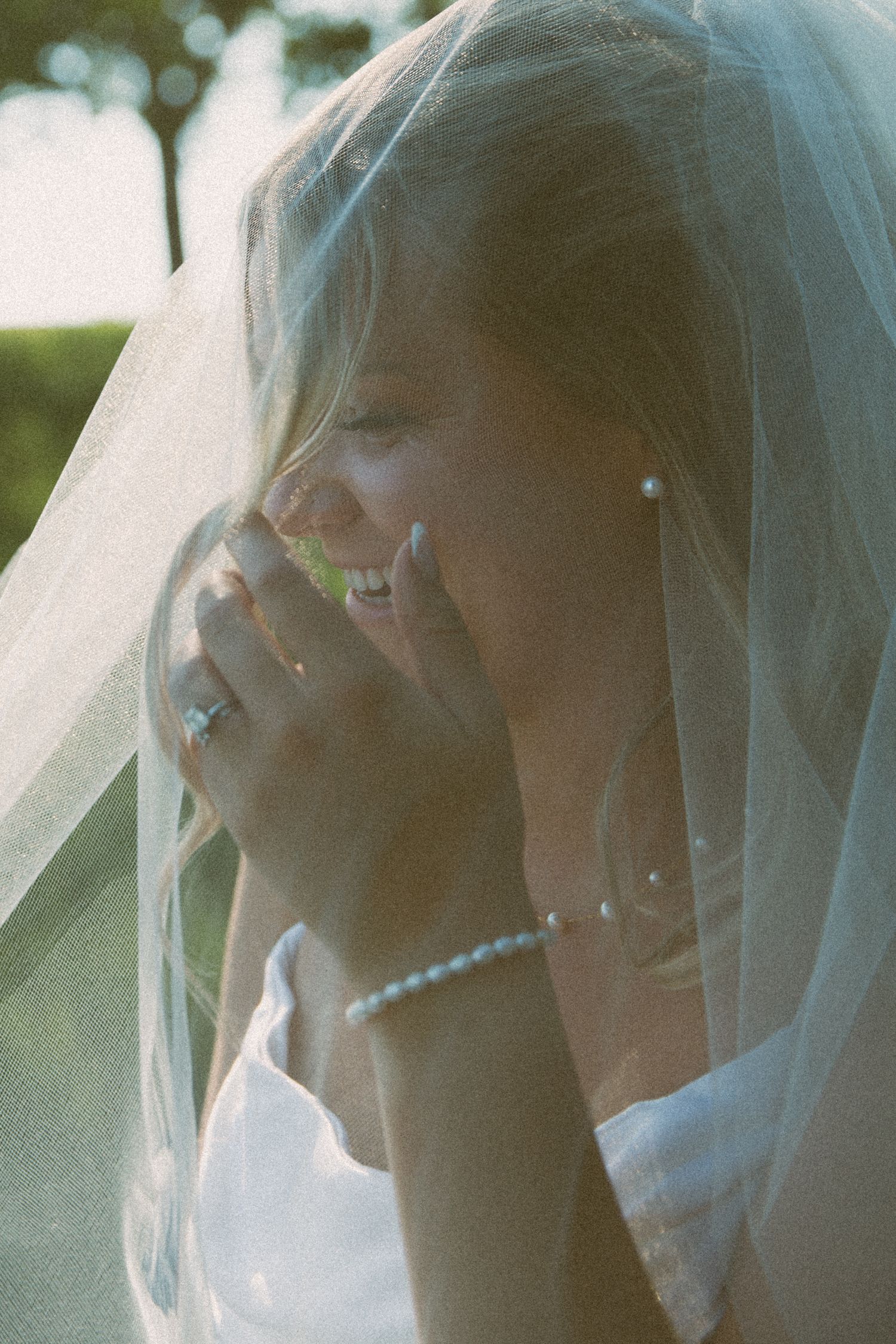 Side profile of a bride with delicate veil and jewelry in soft natural light.