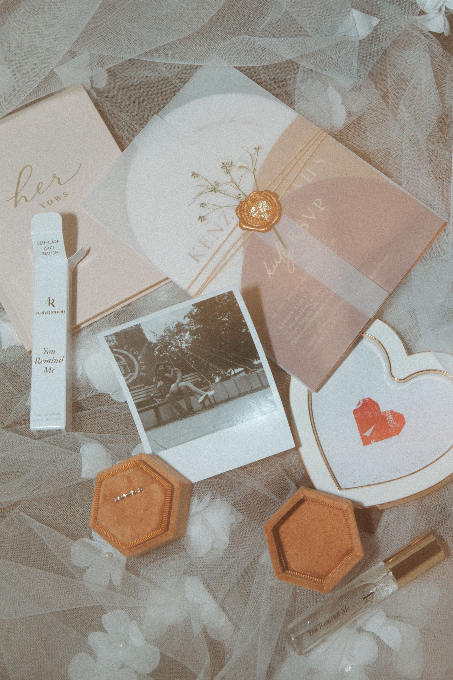 Vintage-style wedding details including invitations, envelopes, Polaroid photo and hexagonal jewelry boxes on tulle fabric.