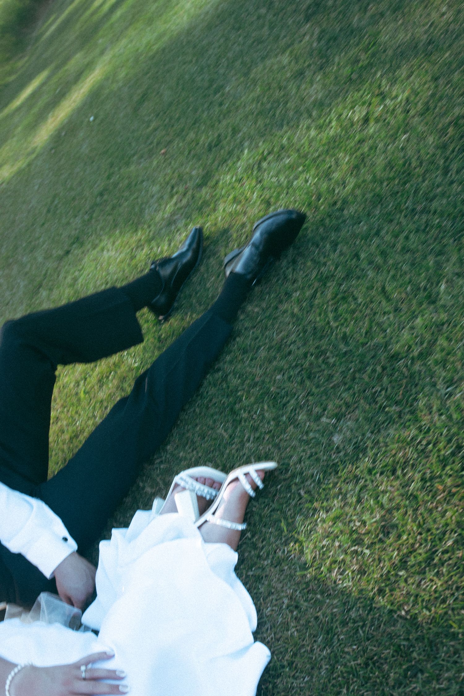 Wedding dress and shoes detail shot on green grass during outdoor photography session.