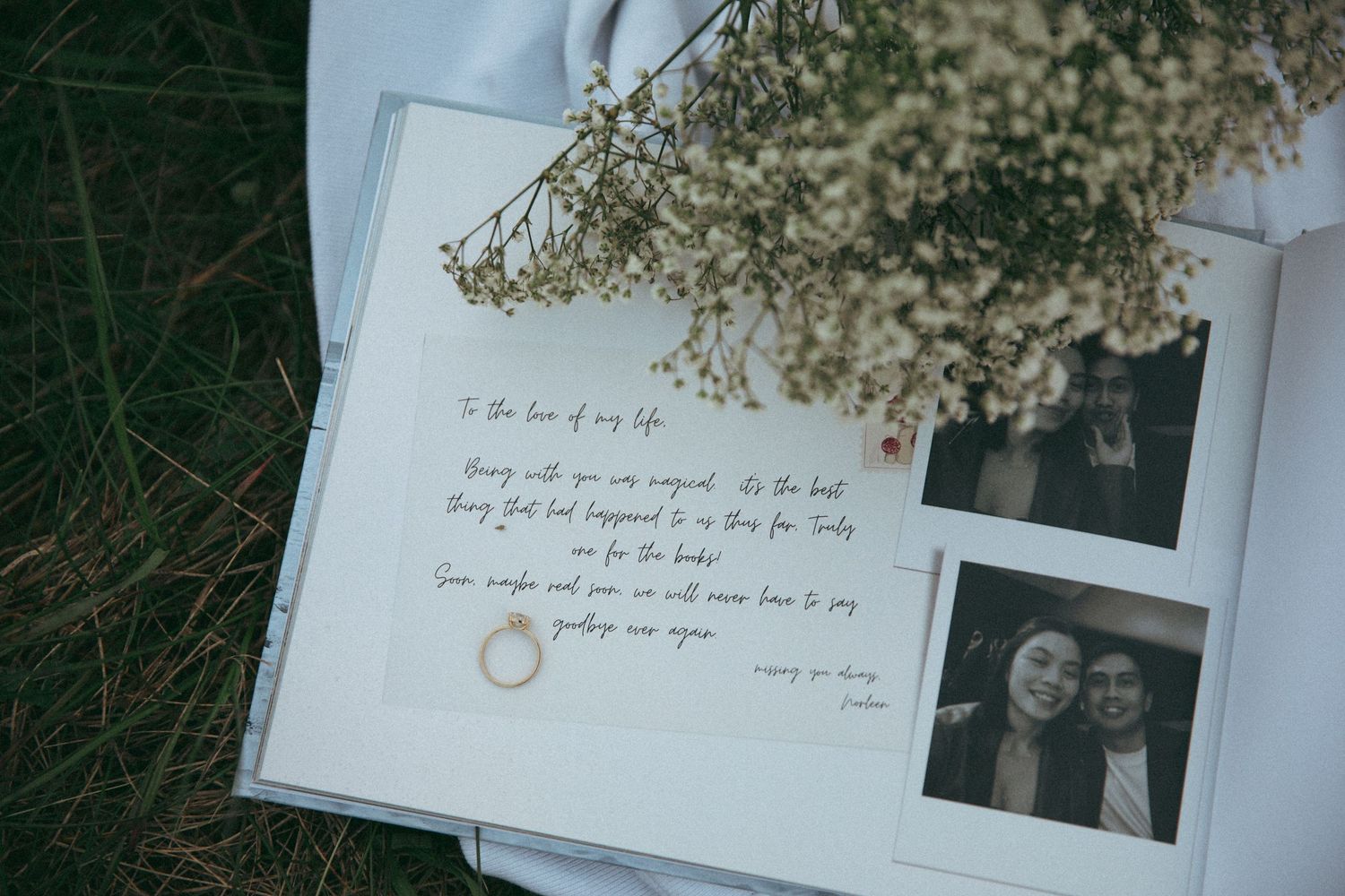 Handwritten wedding vows alongside dried baby's breath flowers and a black and white photo on white paper.