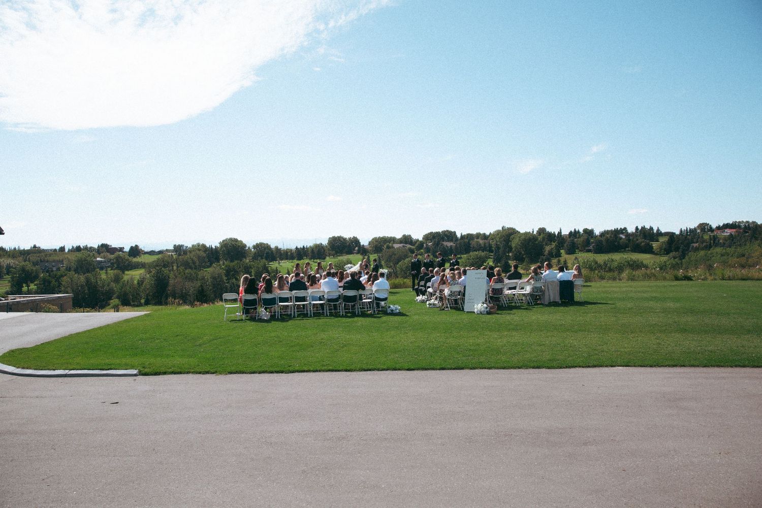 Aerial view of outdoor wedding venue with guests gathered on green lawn.