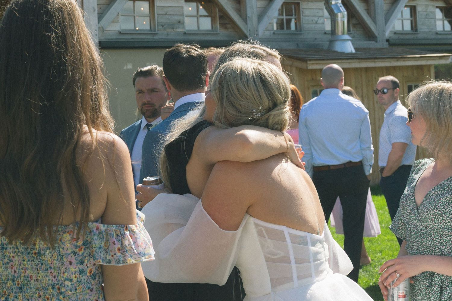 Wedding guests gathered outside a rustic wooden barn structure.