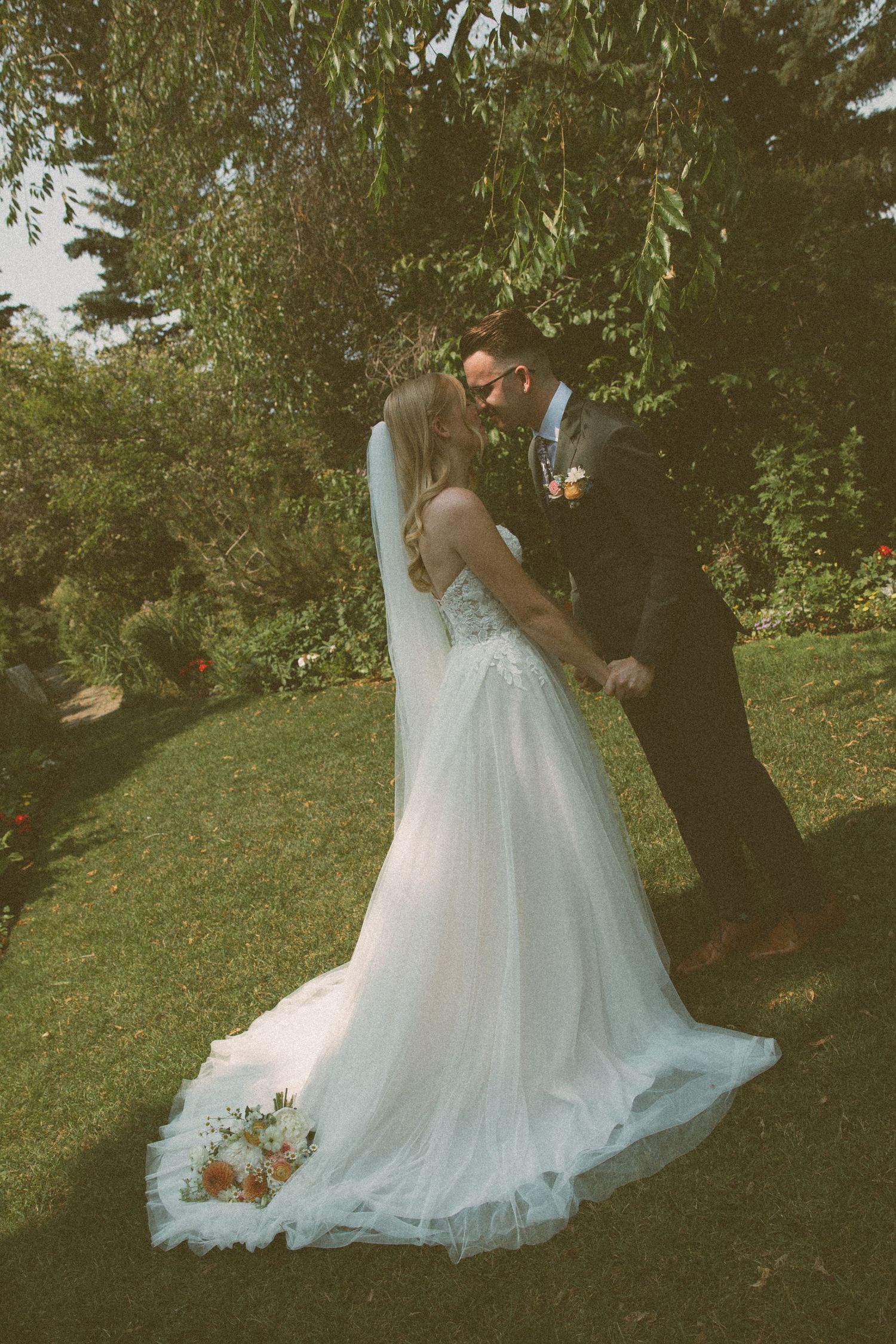 A romantic wedding dip pose with flowing white dress in a garden setting.