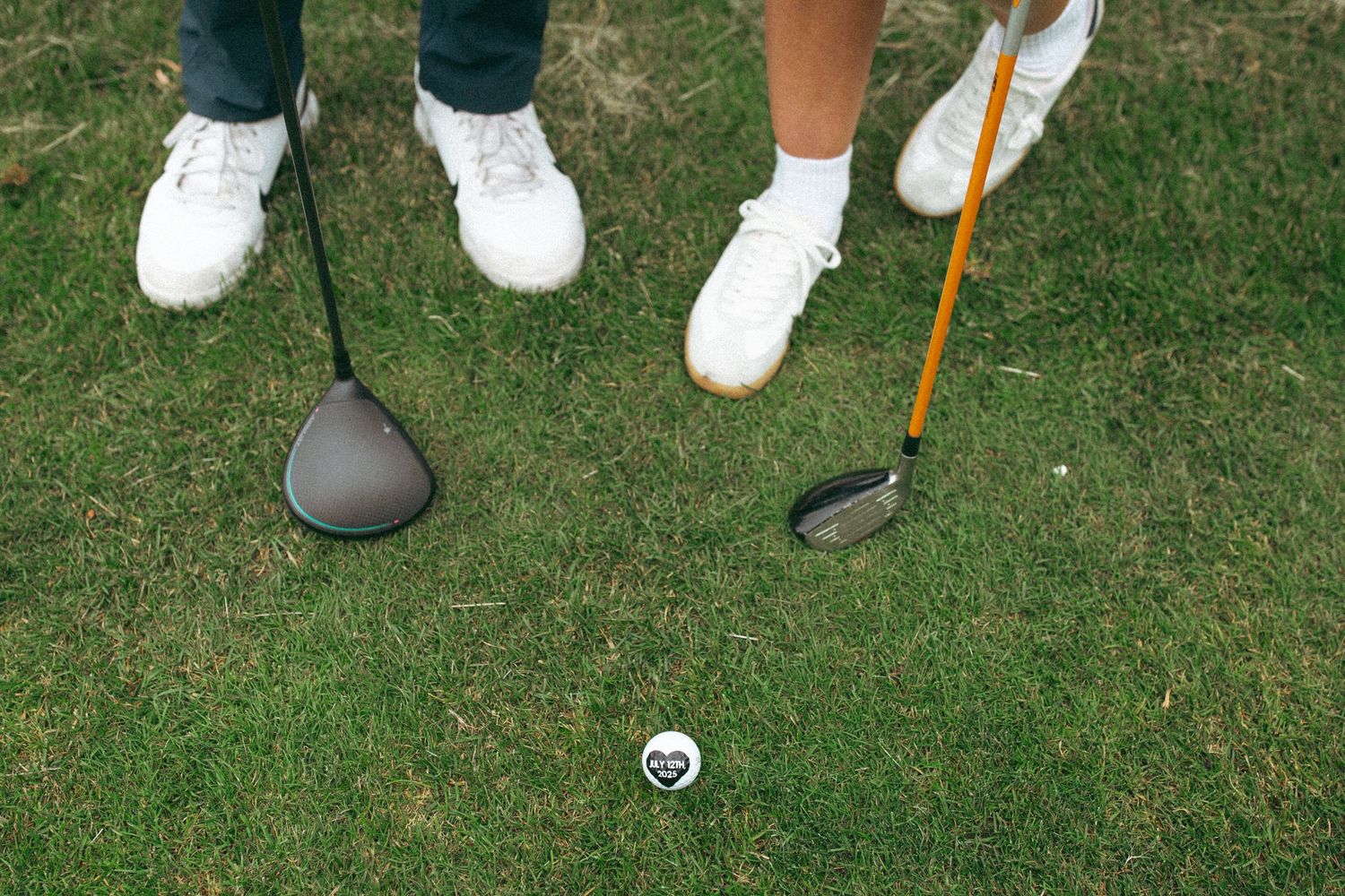 Golf clubs and shoes positioned near ball on green grass.